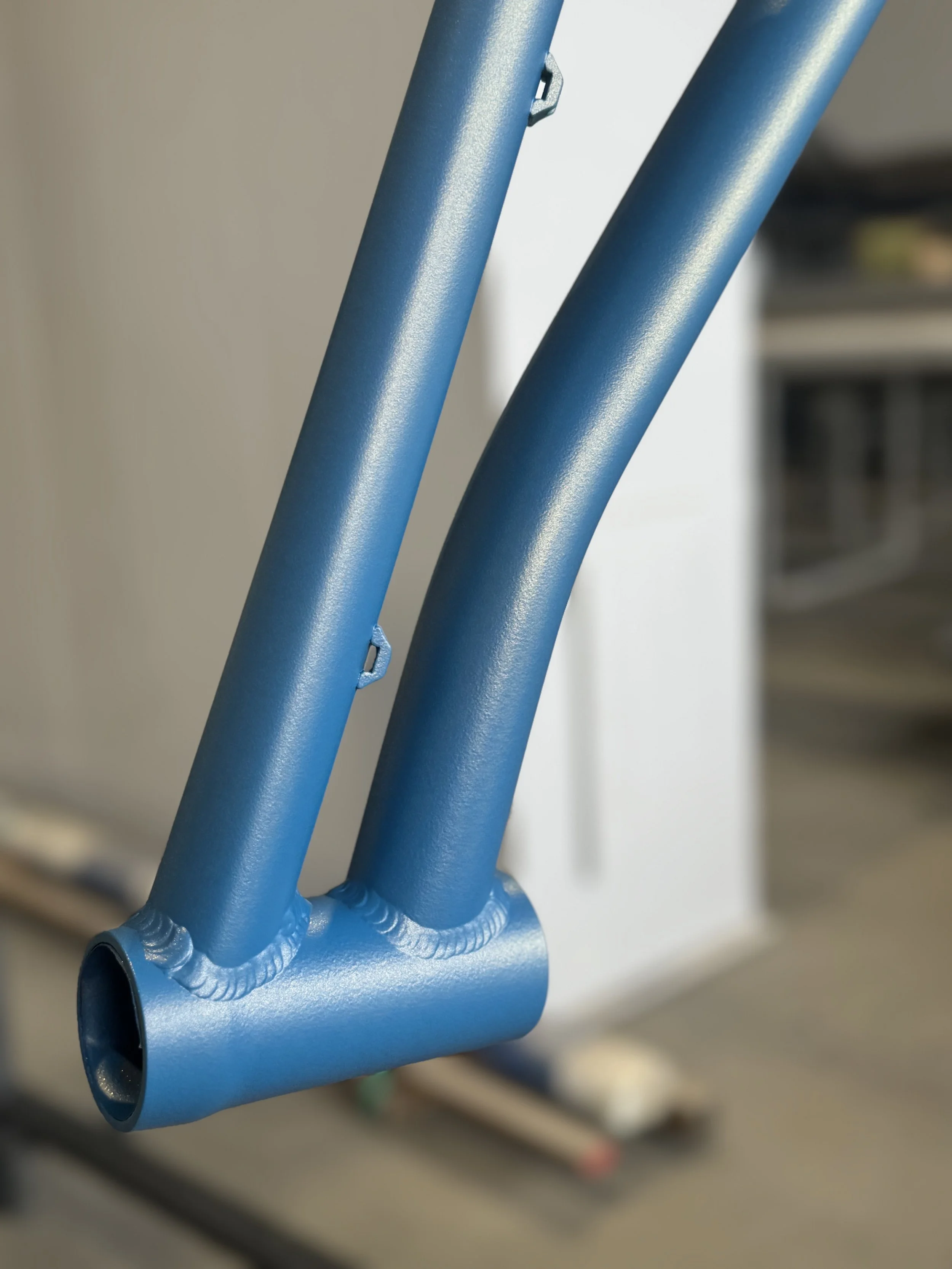 Close-up of blue painted metal pipes joined with welding on an industrial or mechanical equipment.