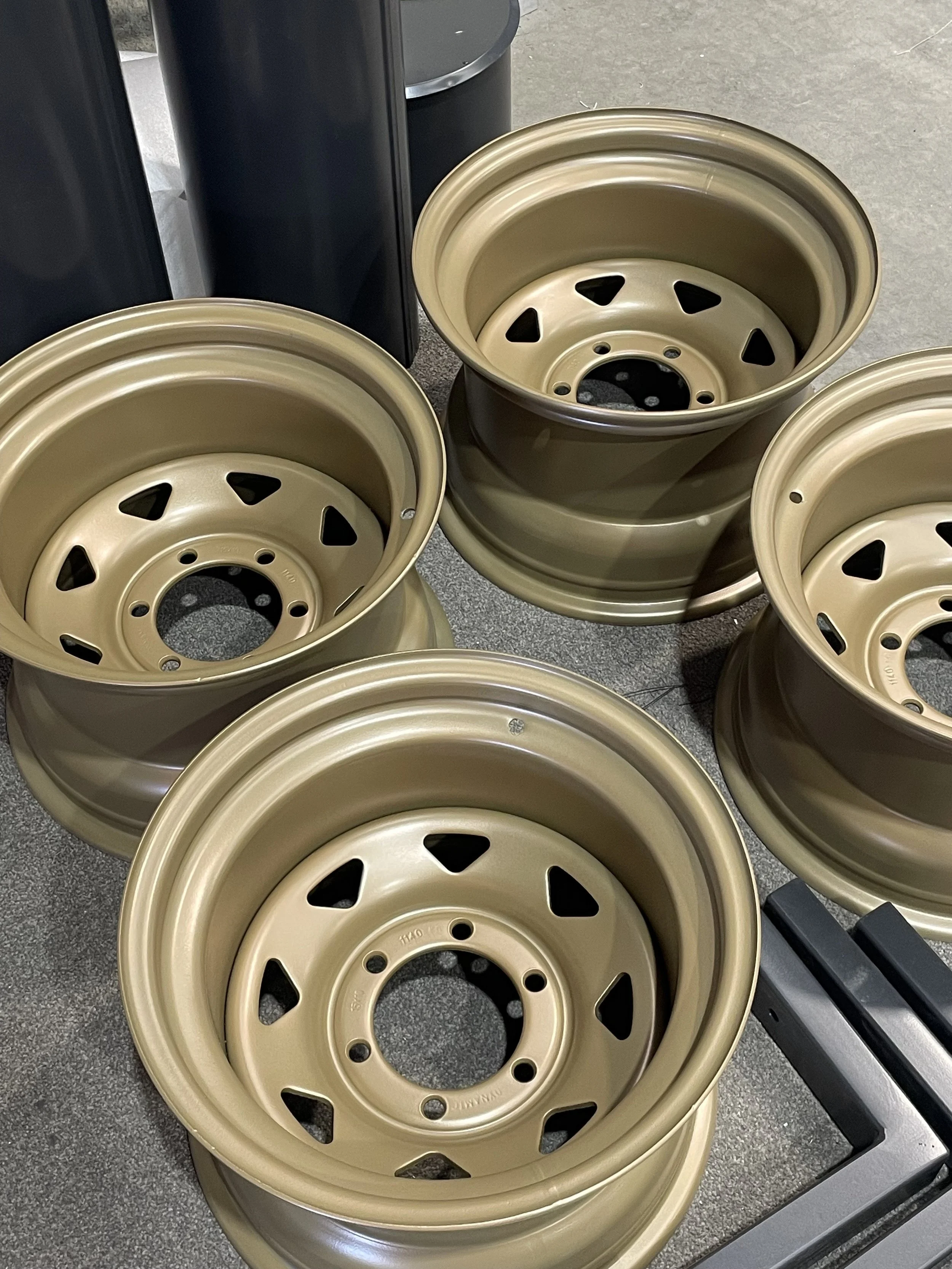 Several beige-colored car wheels stacked on a store floor, with some black shelves and equipment in the background.