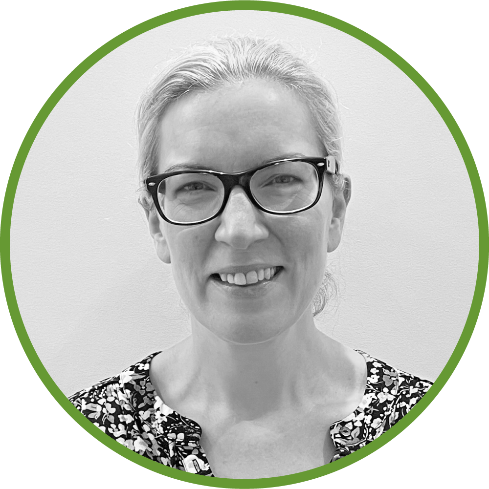 Dr Joanne Spoors wearing glasses and a floral top, smiling, with a green circular border.