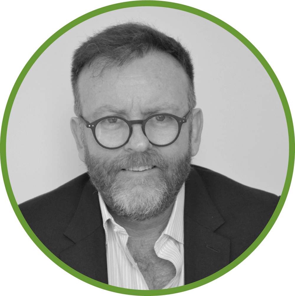 Dr Ian Martin with glasses and beard in a black suit and striped shirt, green circular border.