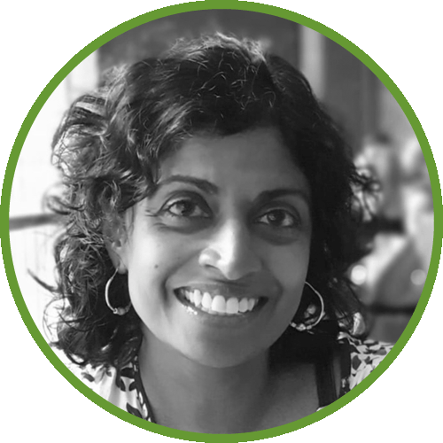 Dr Brinda Paramothayan smiling with curly hair and hoop earrings in a black and white photo with a green border.