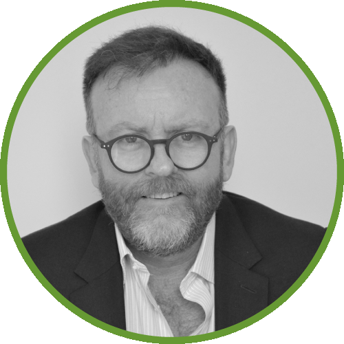 Dr Ian  Martin smiling man wearing glasses and a suit jacket, surrounded by a green circular border.