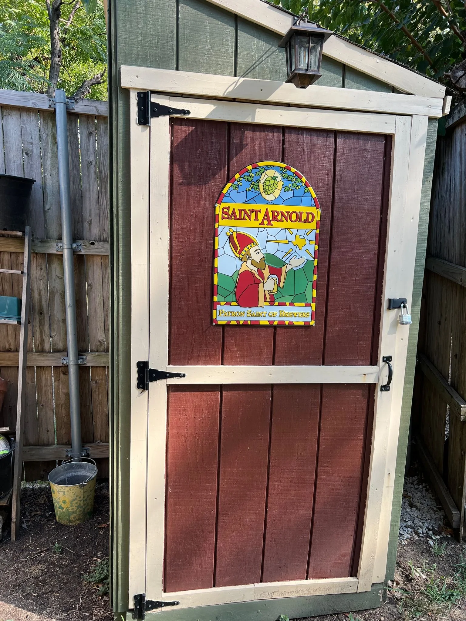 Shed with a Saint Arnold sign on the door, depicting a religious figure in stained glass style, labeled "Patron Saint of Brewers."