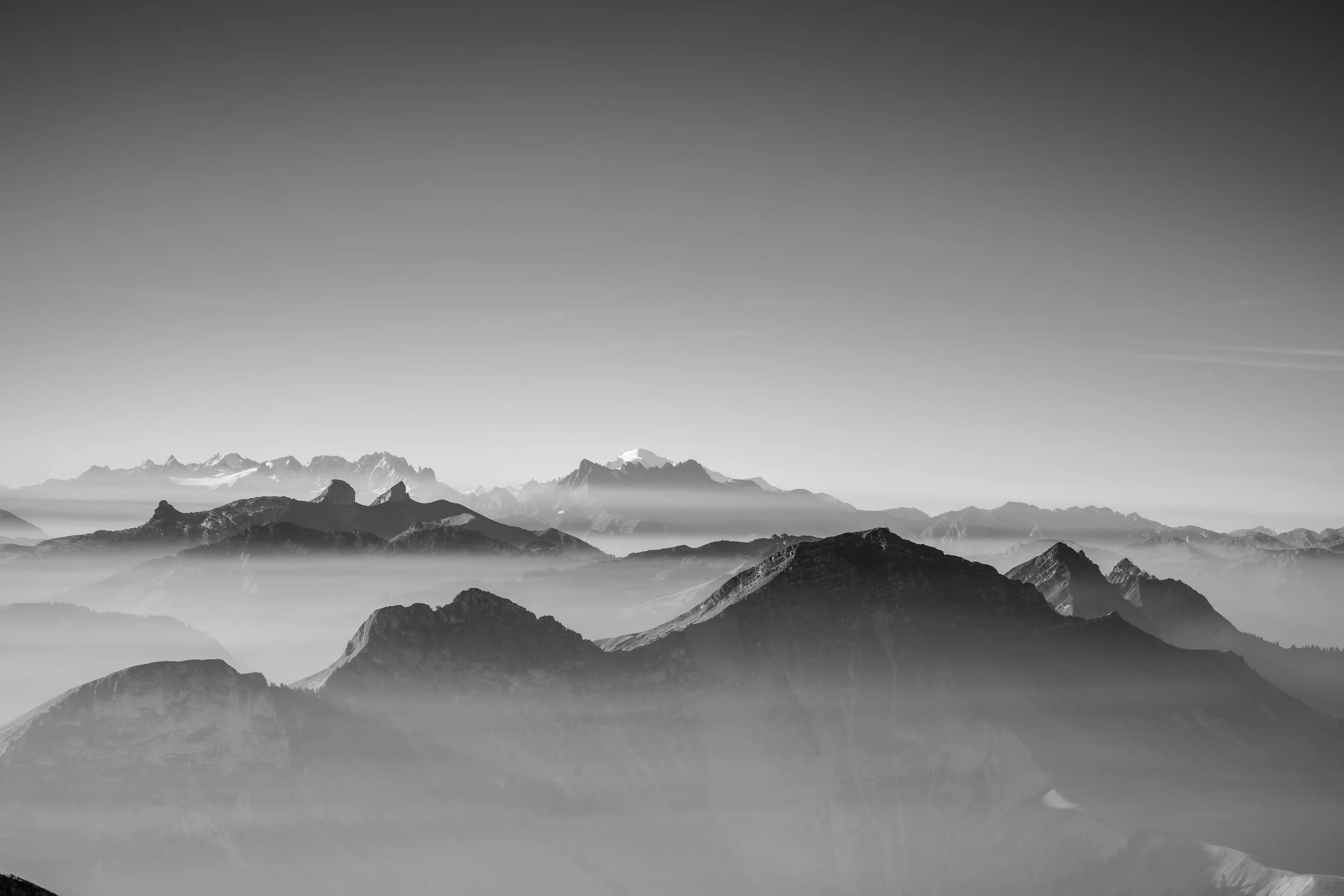 A black and white panorama of the Swiss alps peaking above cloud