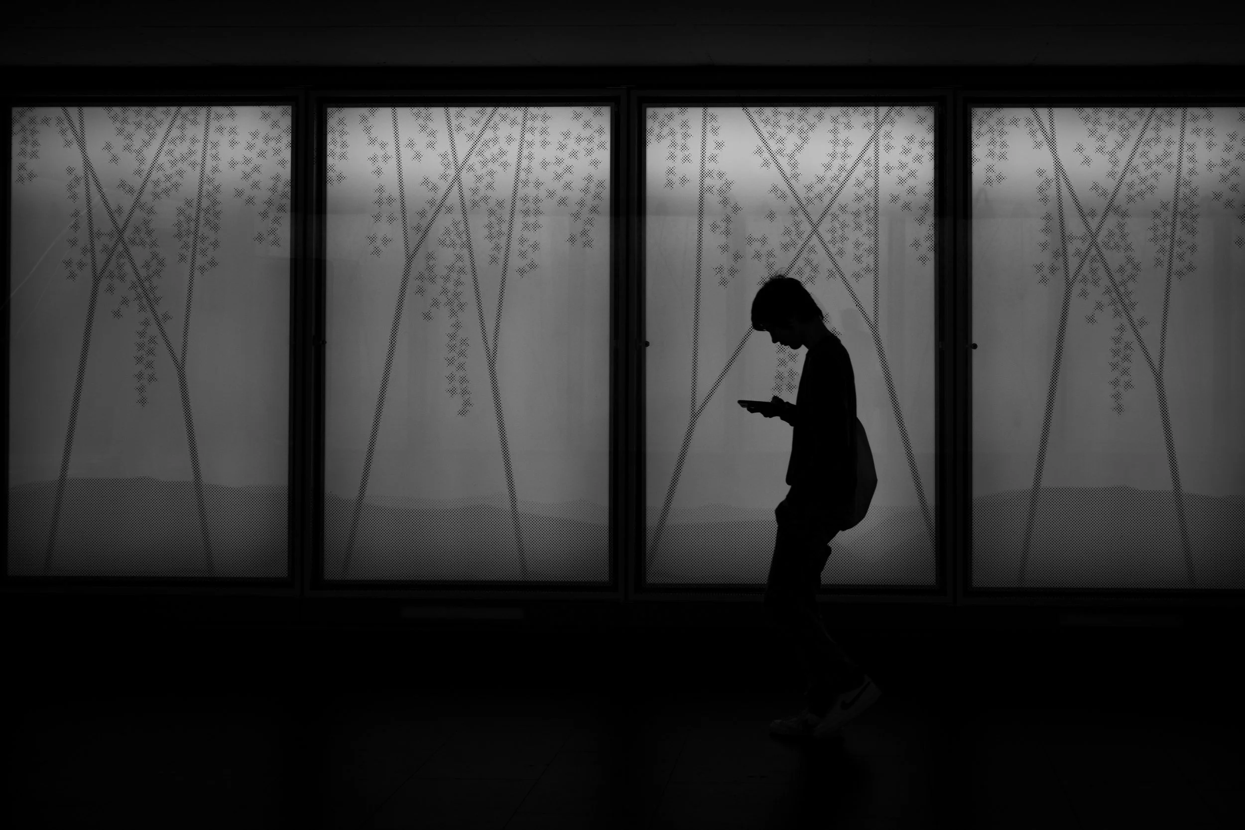 Black and white silhouette of a teenager on his phone