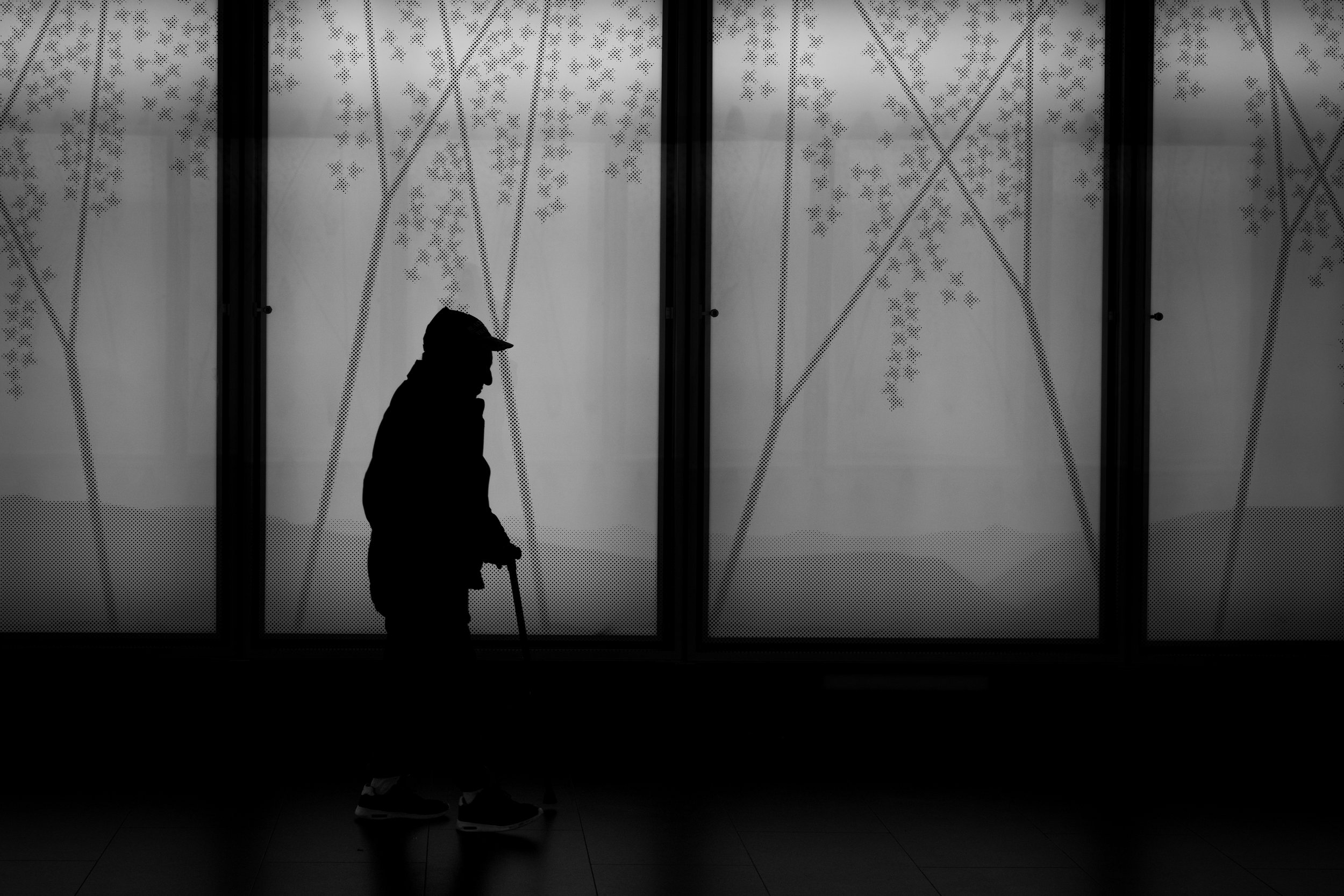 Black and white silhouette of an old man with a walking stick
