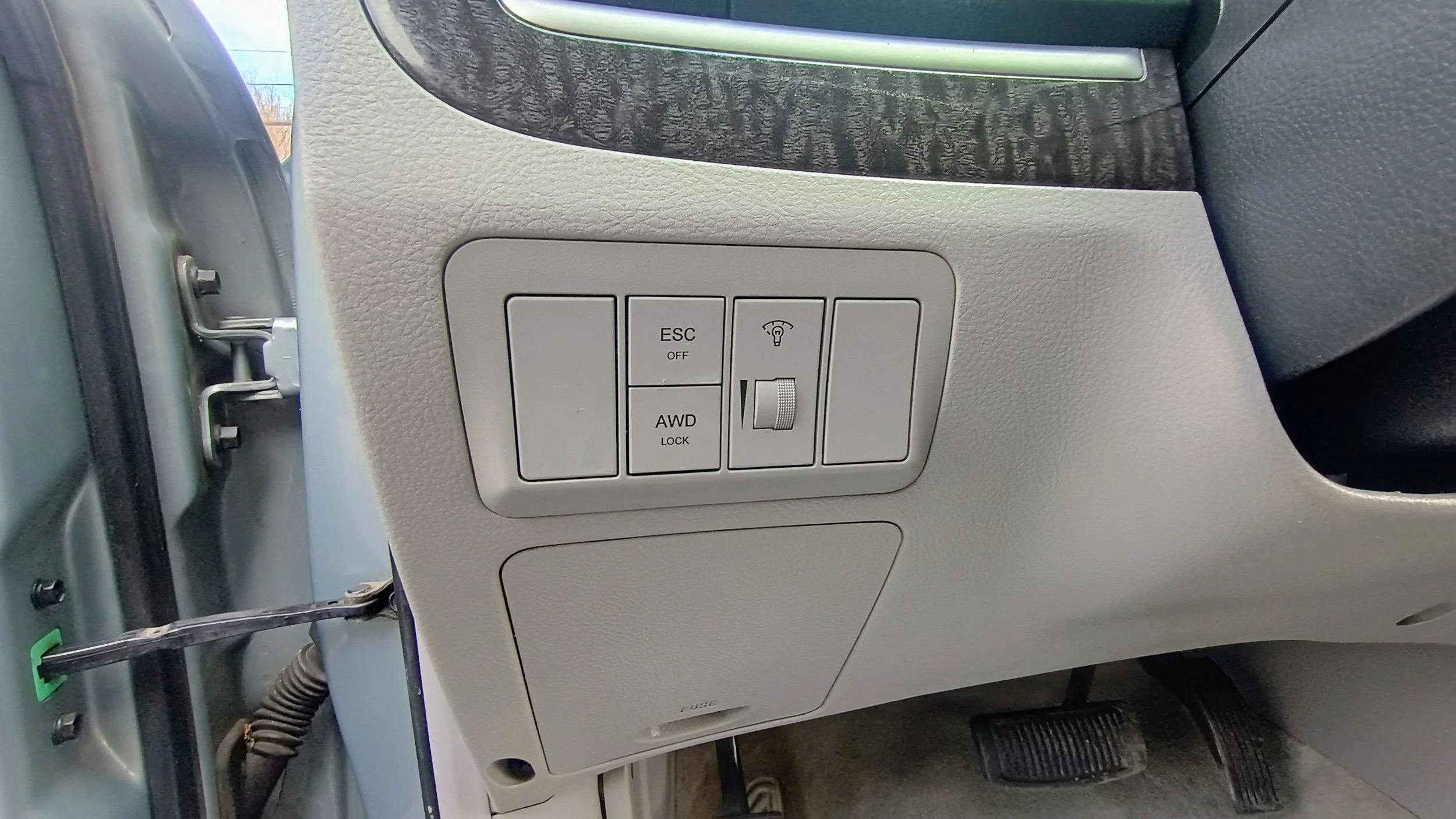 Close-up view of the vehicle's dashboard panel with buttons for ESC off, AWD lock, and a dial for headlight adjustment.
