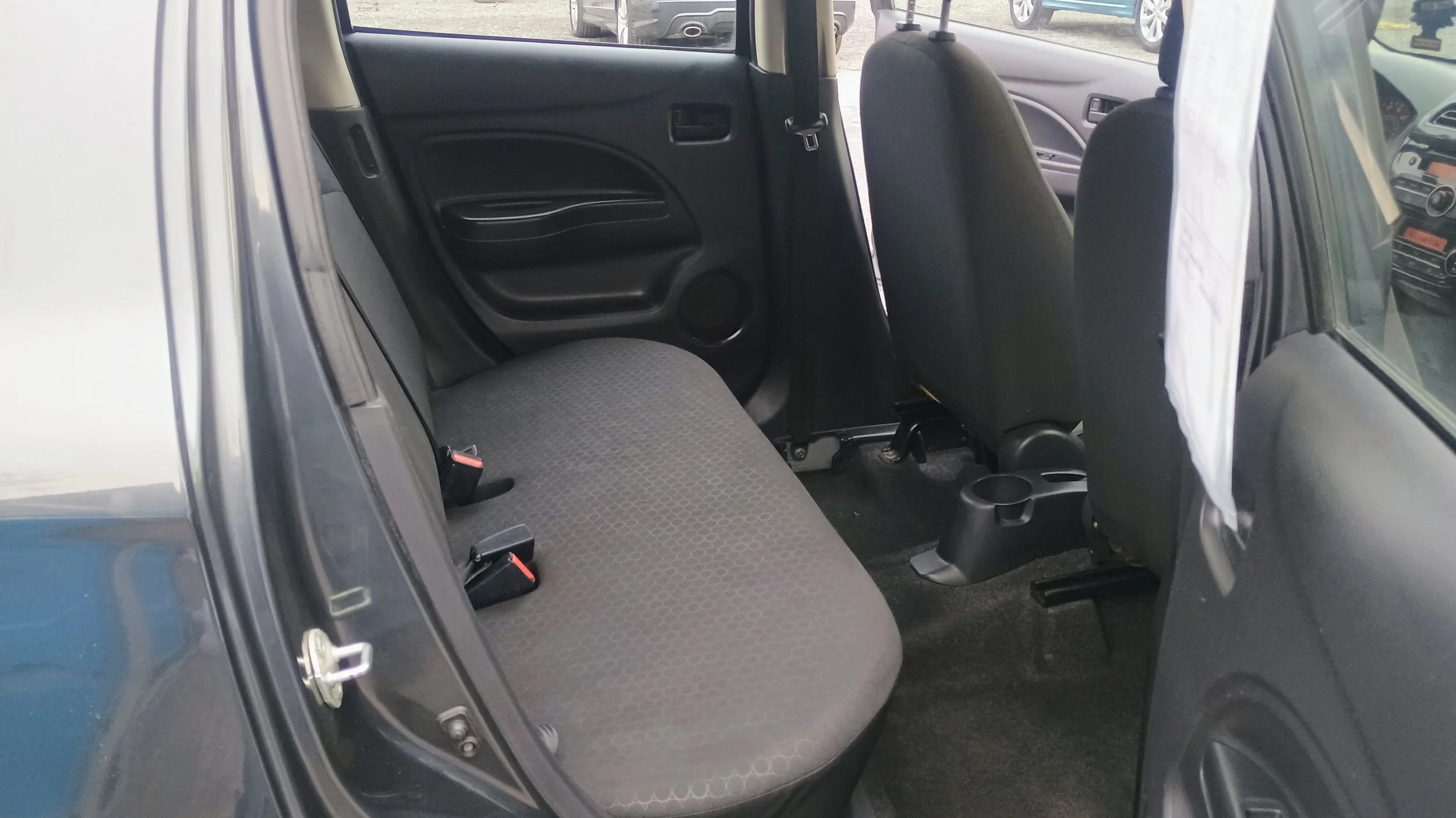 Image of the rear interior of a car showing a bench seat with black and gray fabric, rear side door, and front seats.