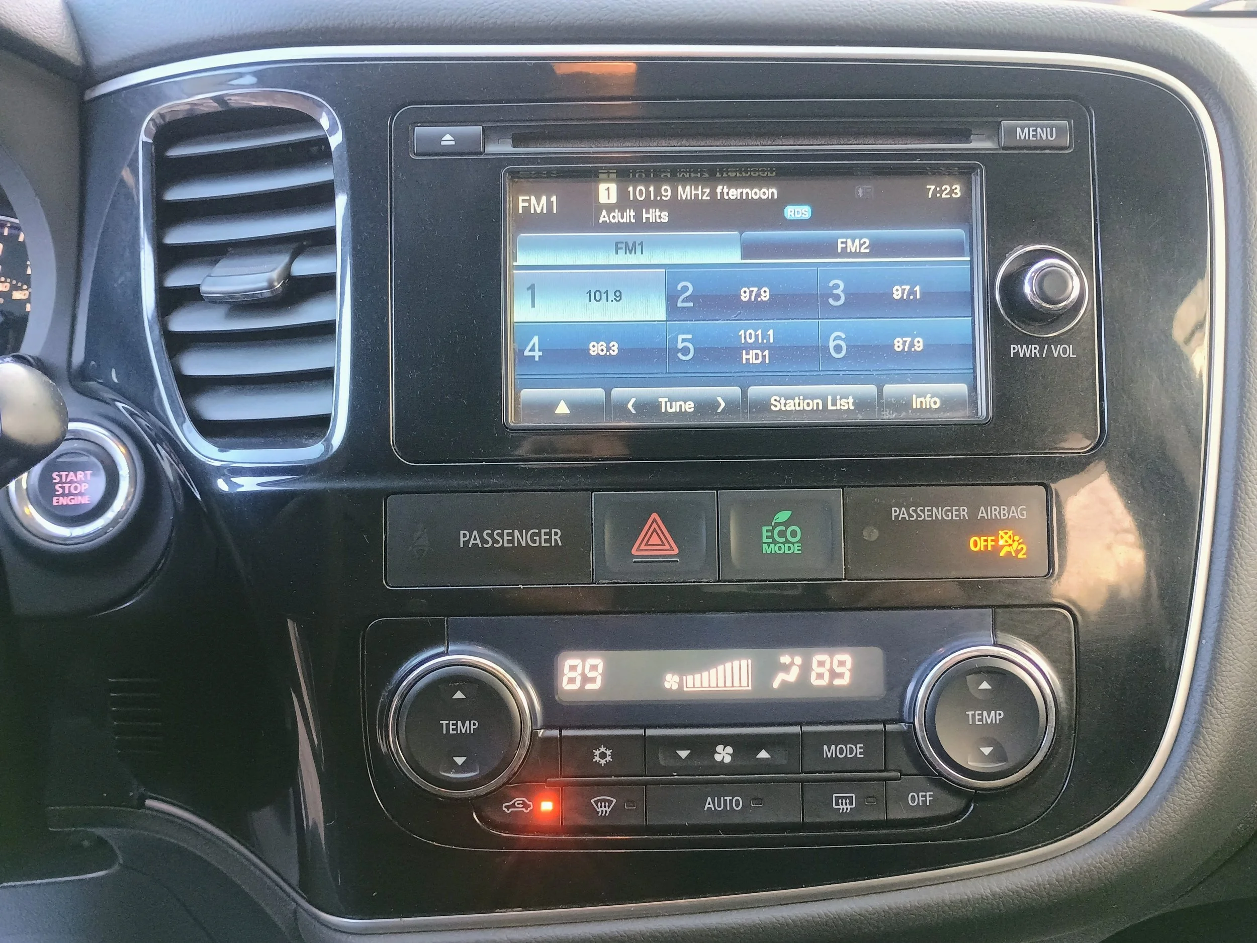 The car's dashboard showing the infotainment system, climate controls, and the start/stop engine button.