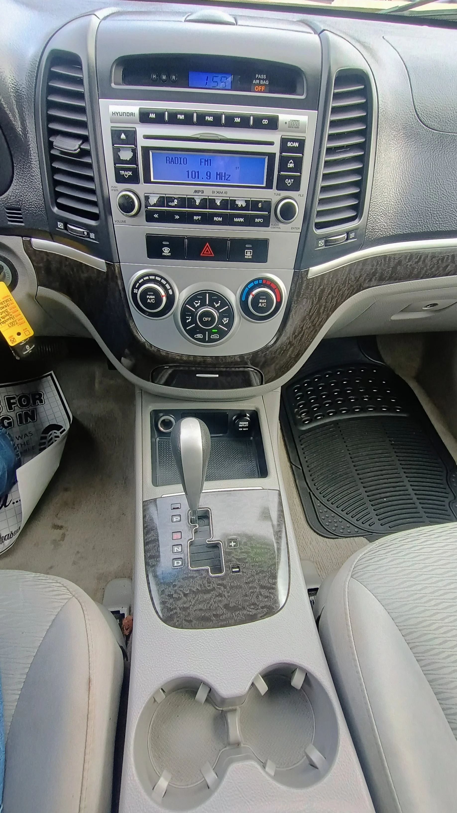 Inside view of a car's dashboard, center console, and front seats showing a gear shift, cup holders, and climate controls.