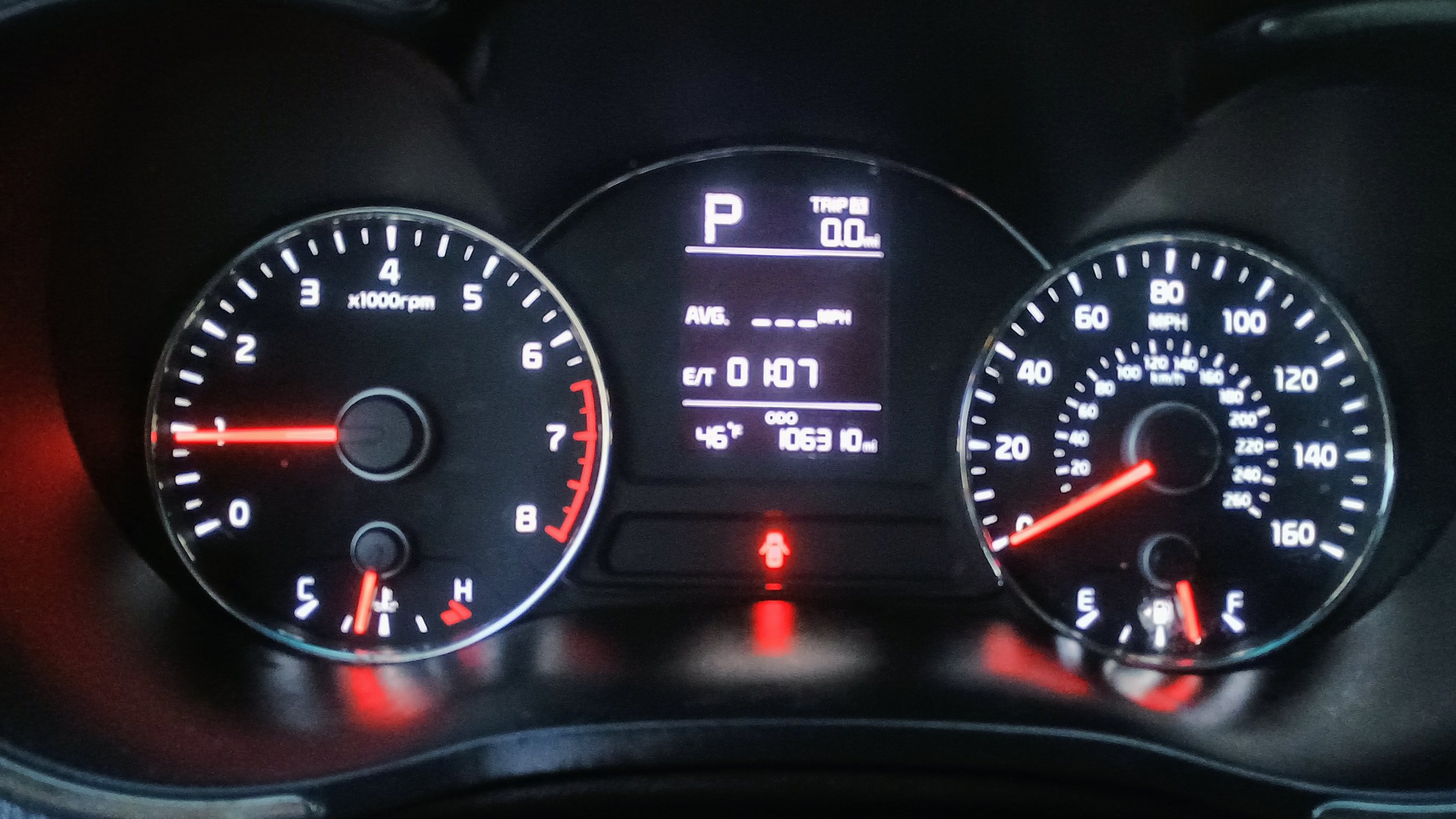 Car dashboard showing speedometer, tachometer, and digital display with parking gear, odometer reading 106310 miles, and warning lights.