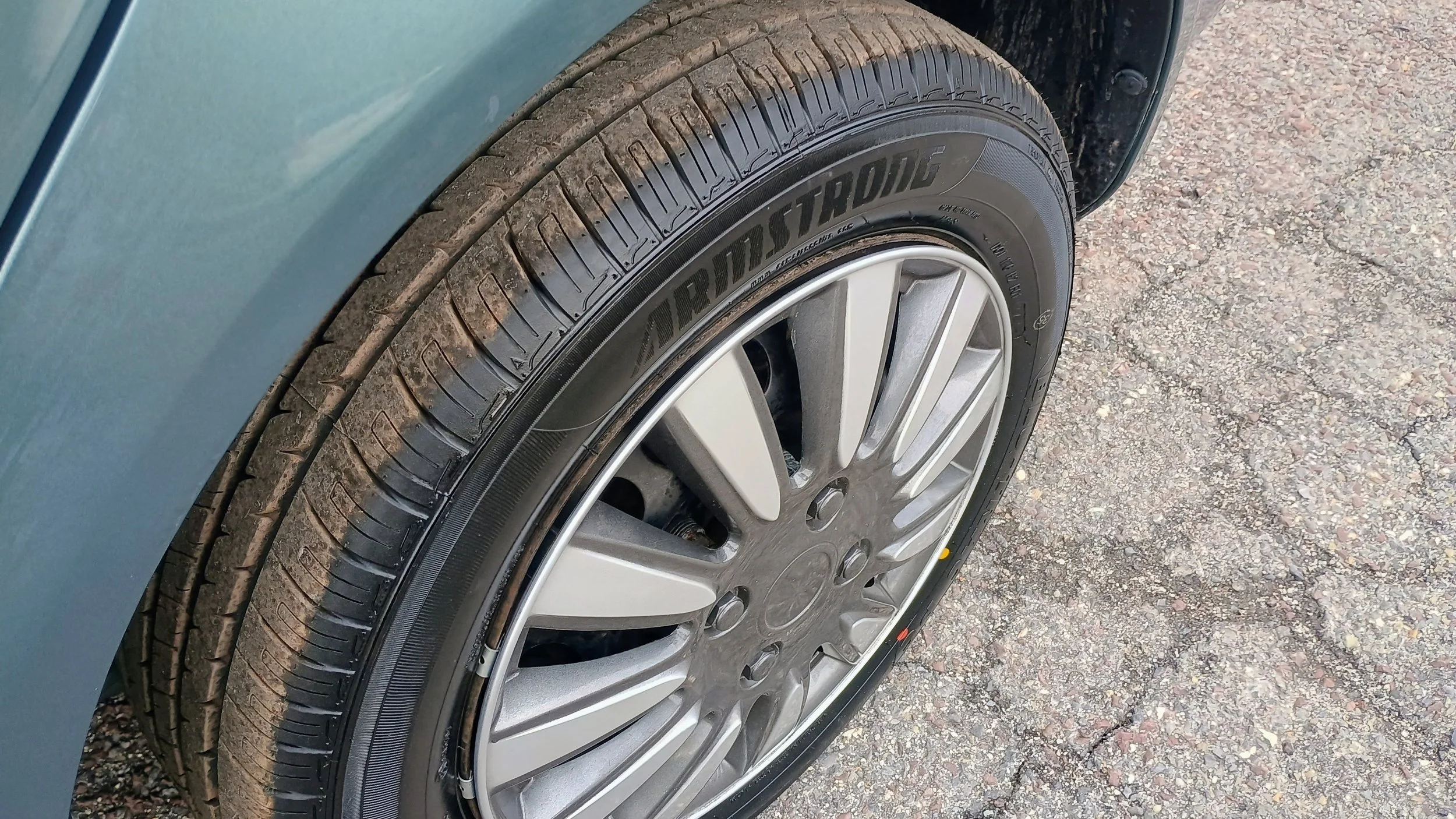 Close-up of a car tire and rim on asphalt, with the tire brand 'Ardius Stang' visible.