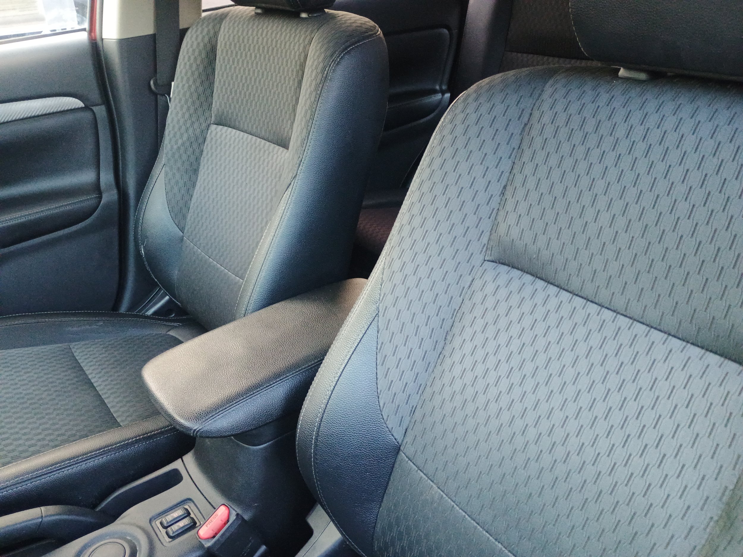 Front passenger and driver seats of a car with black and gray fabric upholstery.