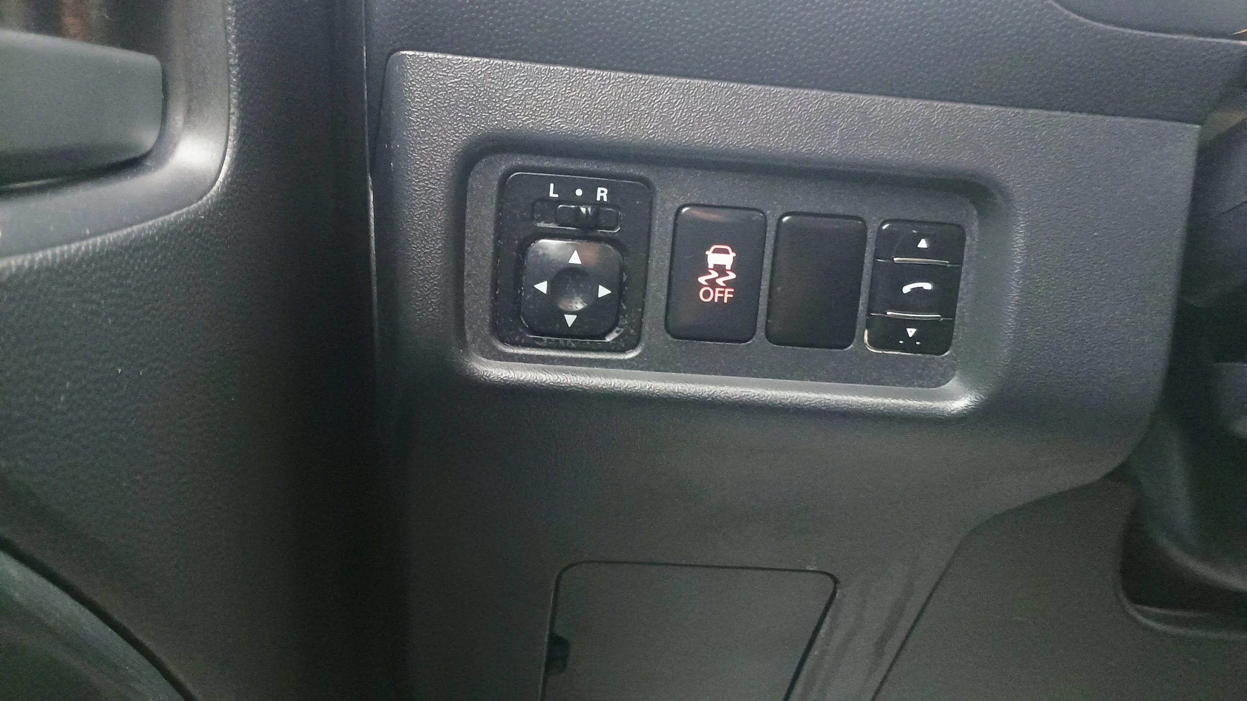 Car interior with control panel featuring side mirror adjustment, vehicle stability off indicator, and phone control buttons.