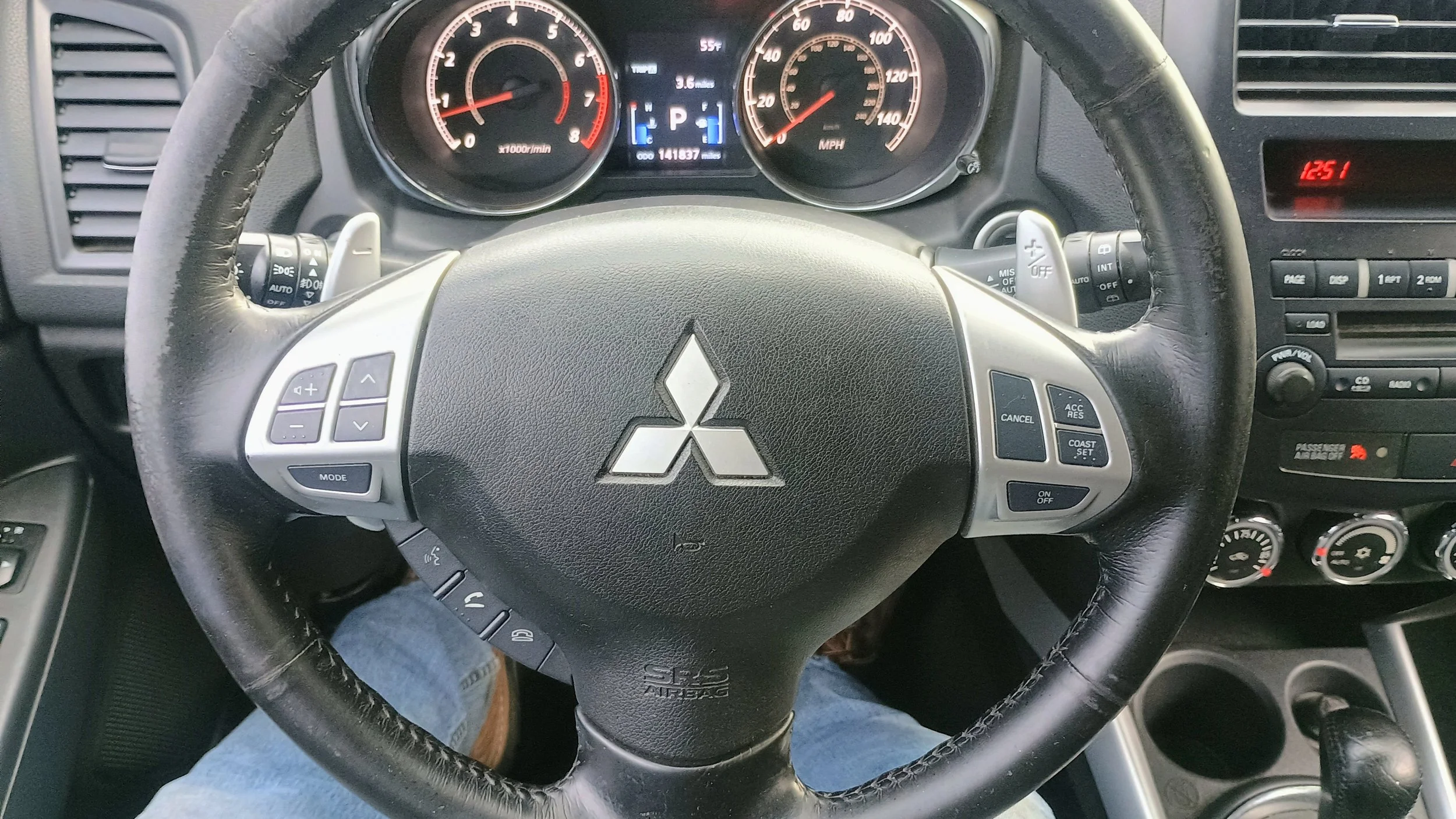 Dashboard of a Mitsubishi vehicle with speedometer, tachometer, and infotainment system, showing the time as 12:51.