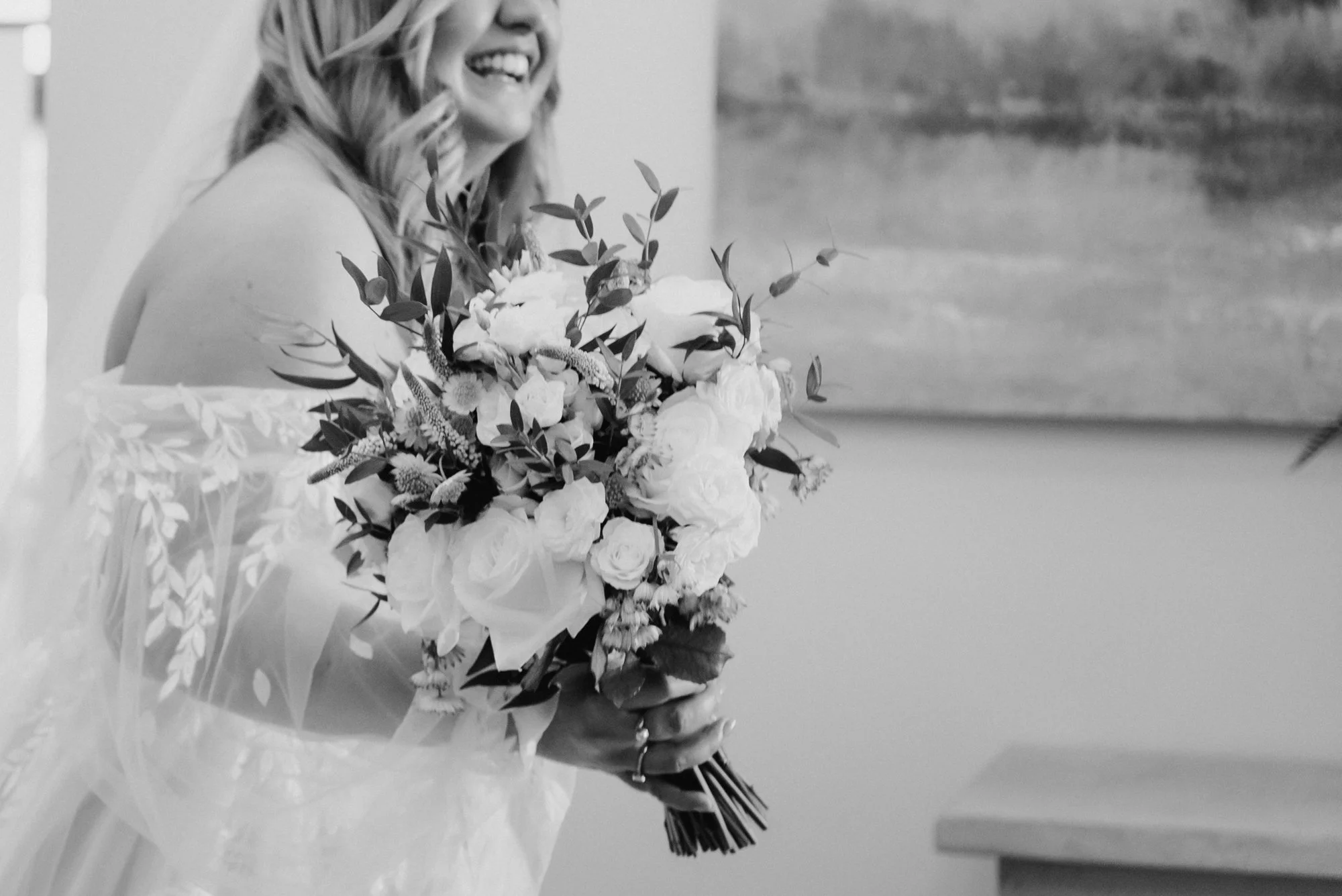 A woman in a wedding dress holding a bouquet of flowers, smiling.