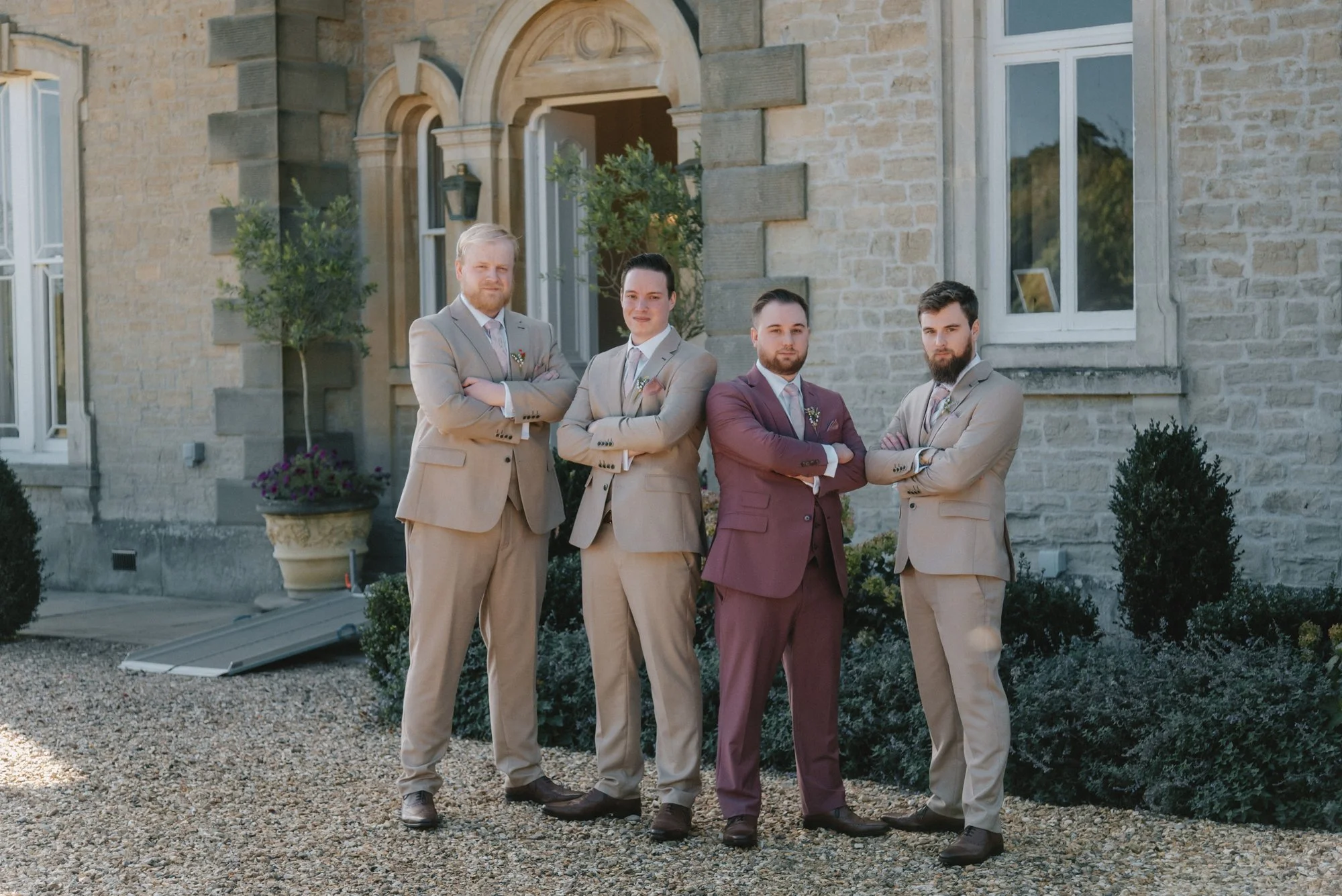Four men in suits standing with arms crossed in front of a stone building.