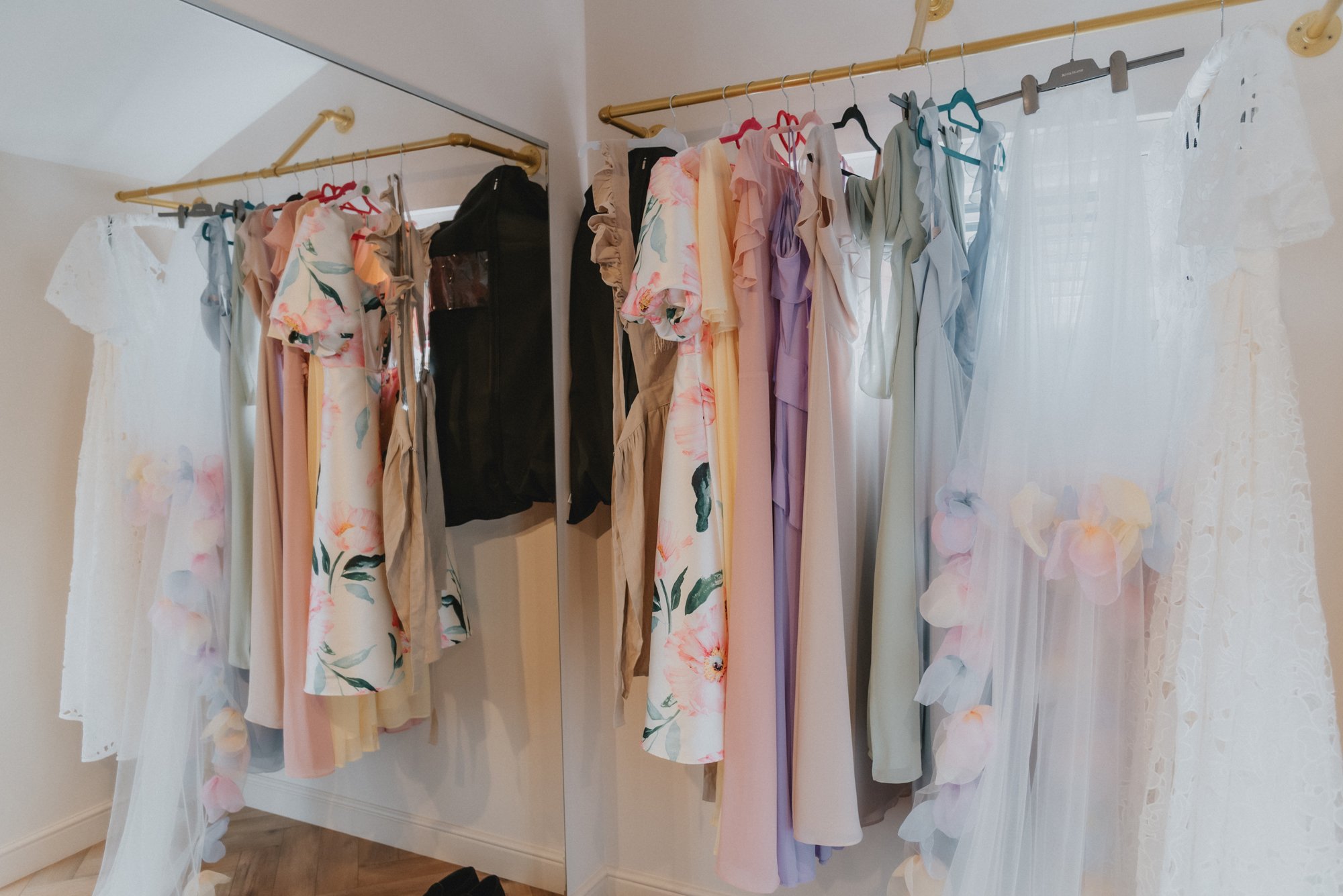 Clothing rack with dresses and wardrobe doors with a mirror reflecting various dresses.