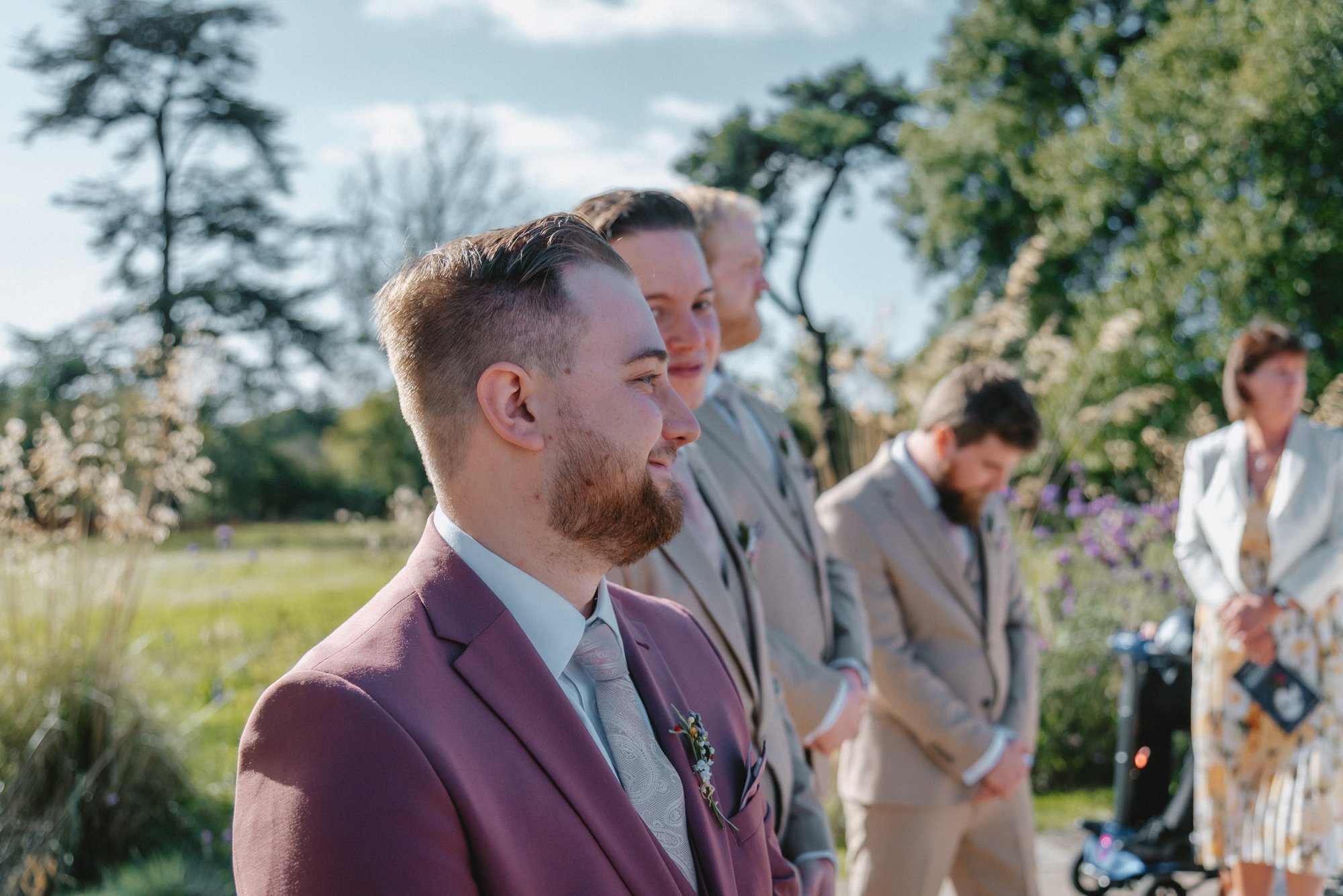 Groom and groomsmen standing outdoors during a wedding ceremony
