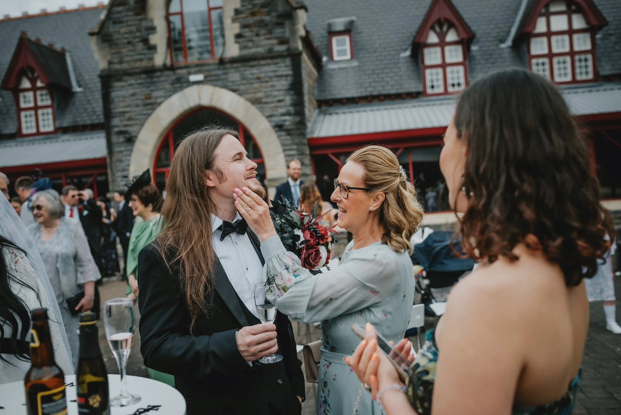 People celebrating at a wedding reception outside with a bride and groom in front of a historic building.