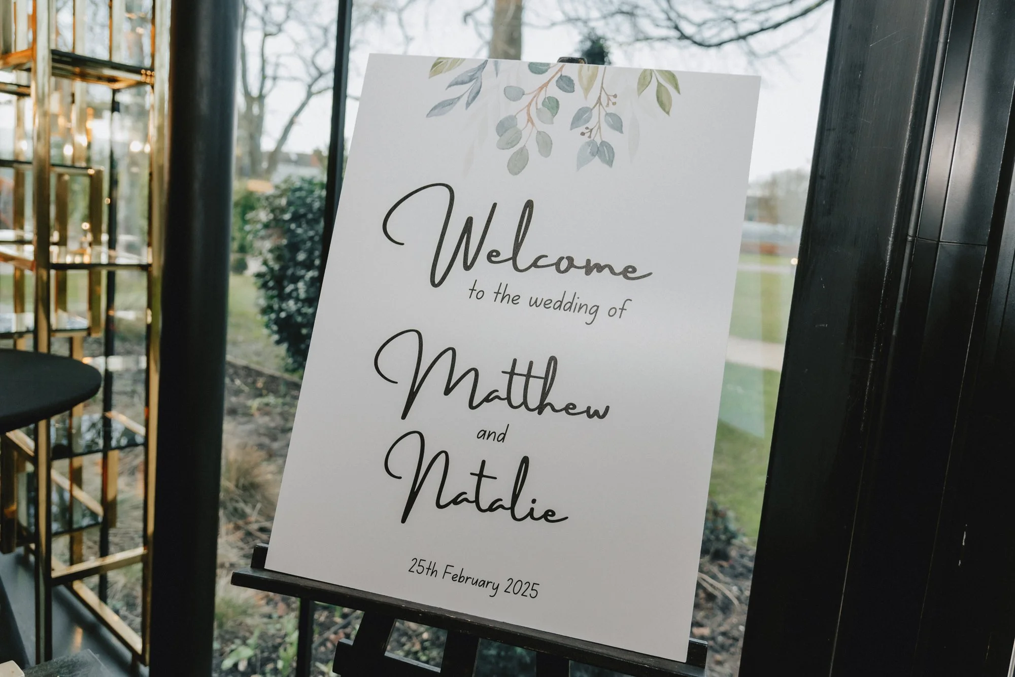 Welcome sign for Matthew and Natalie at their wedding, dated 25th February 2025, decorated with leafy illustrations at the top.