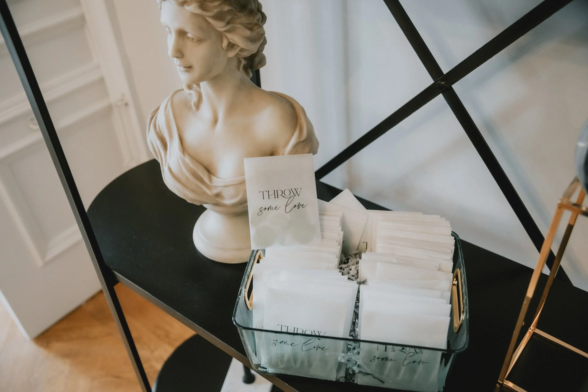 A decorative table displays a bust sculpture of a woman and a tray of white cards with a sign that reads 'Throw some love.'