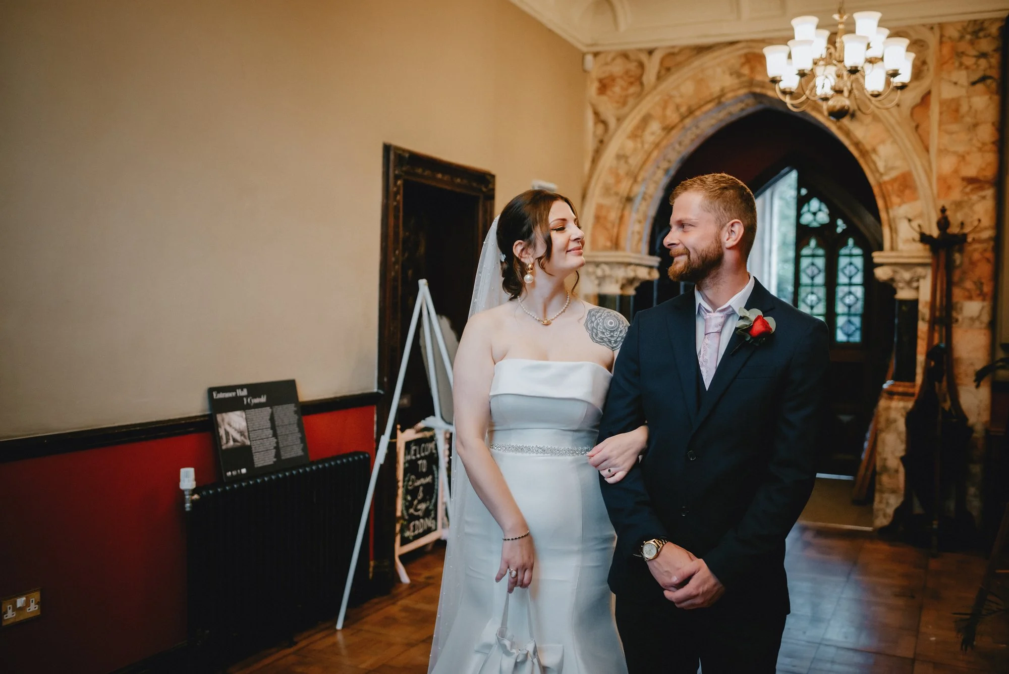 A bride and groom standing together inside a decorated venue, looking at each other.