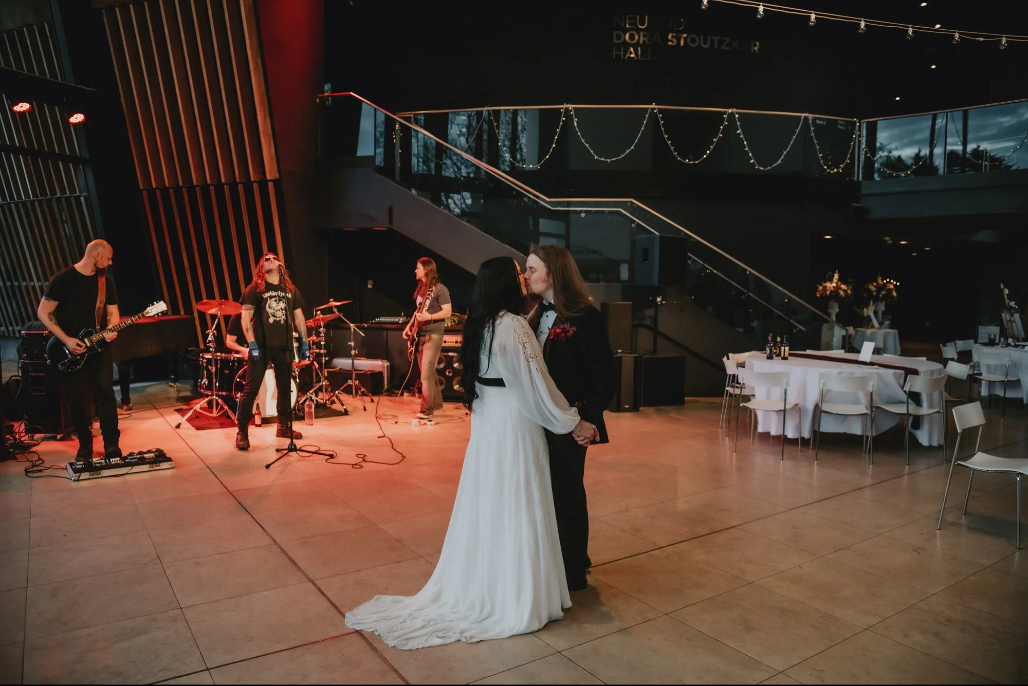 Bride and groom sharing a dance in a wedding reception hall with a live band playing in the background.