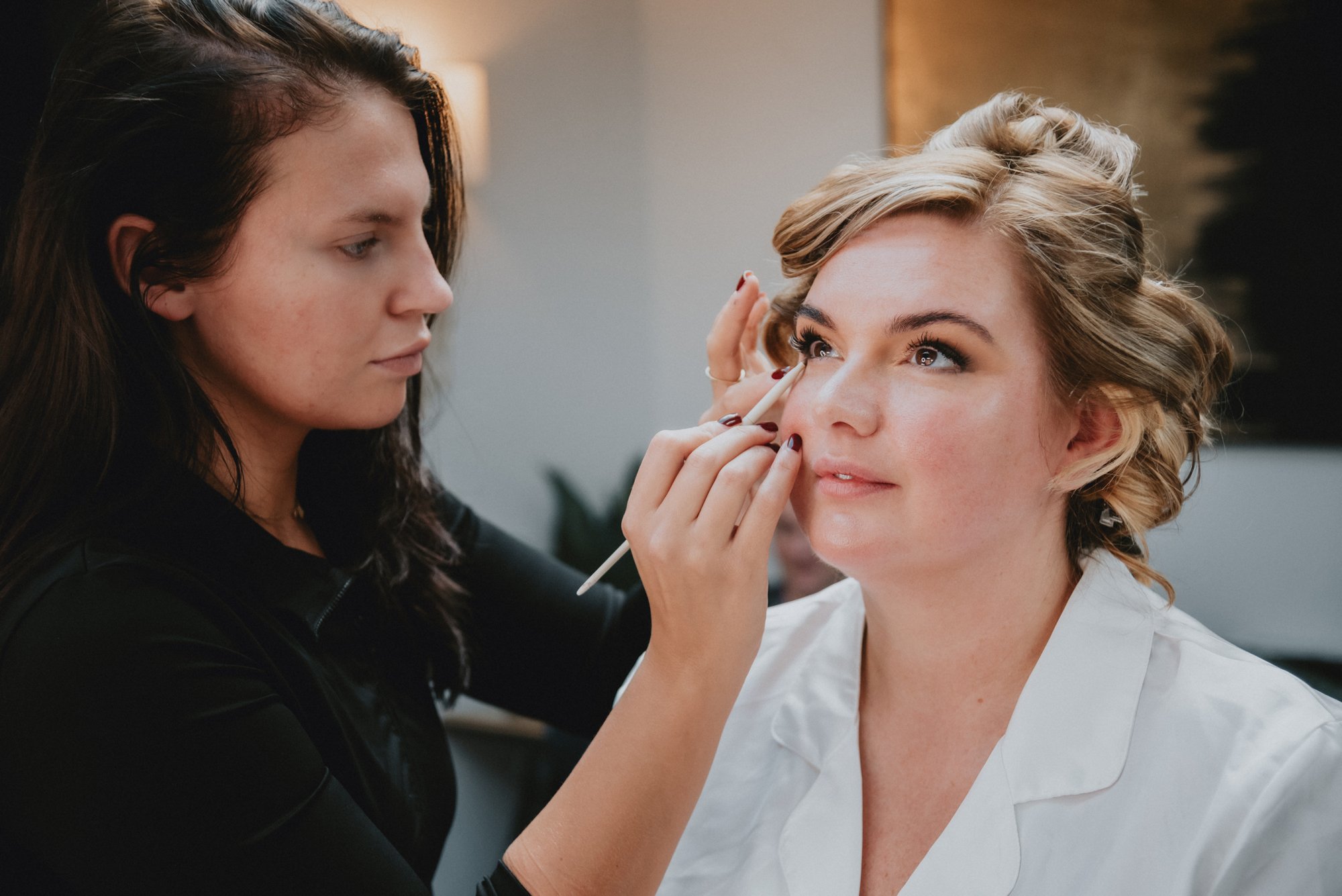 Makeup artist applying makeup to woman's face.