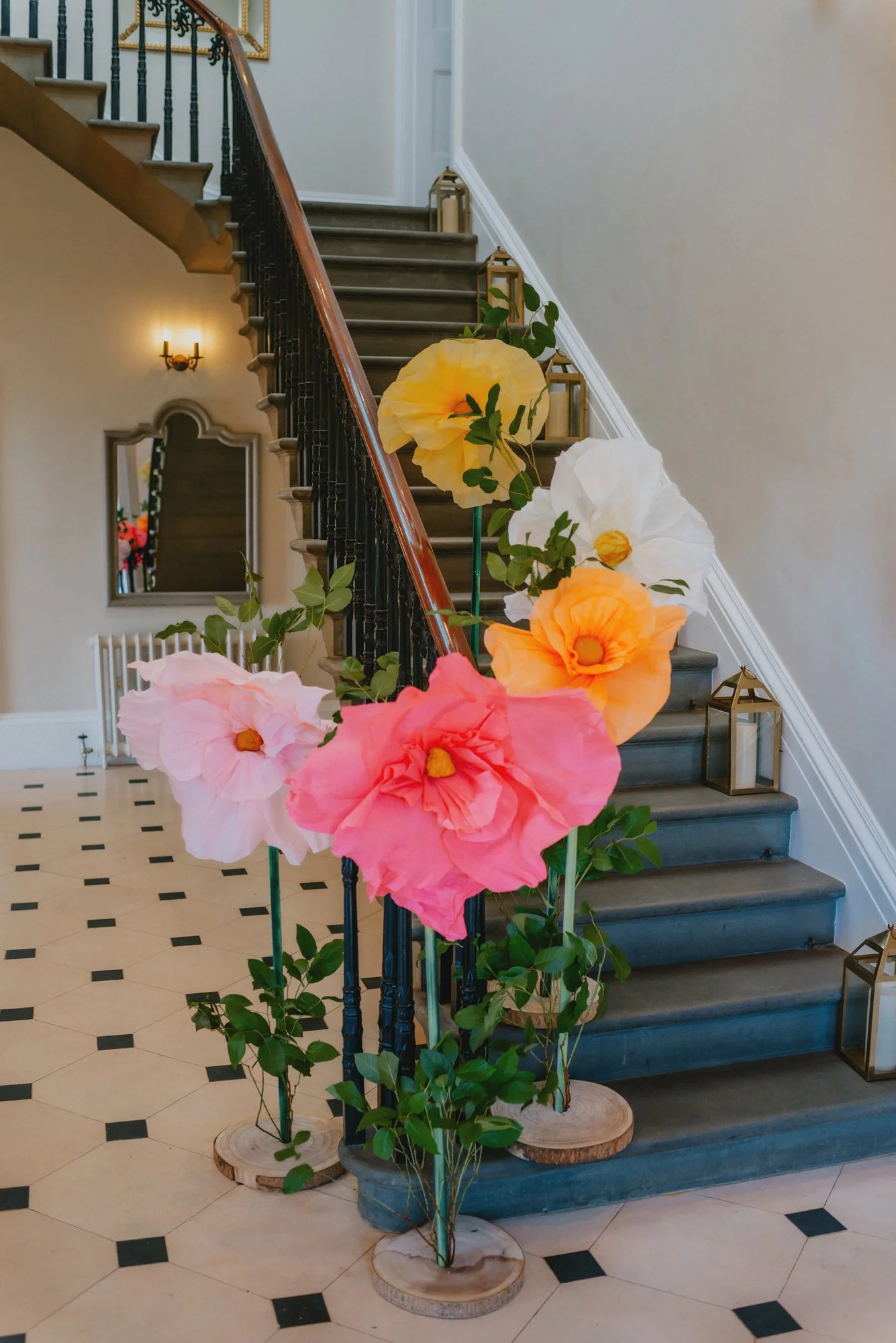 Colorful paper flowers decorating a staircase in an elegant indoor space.