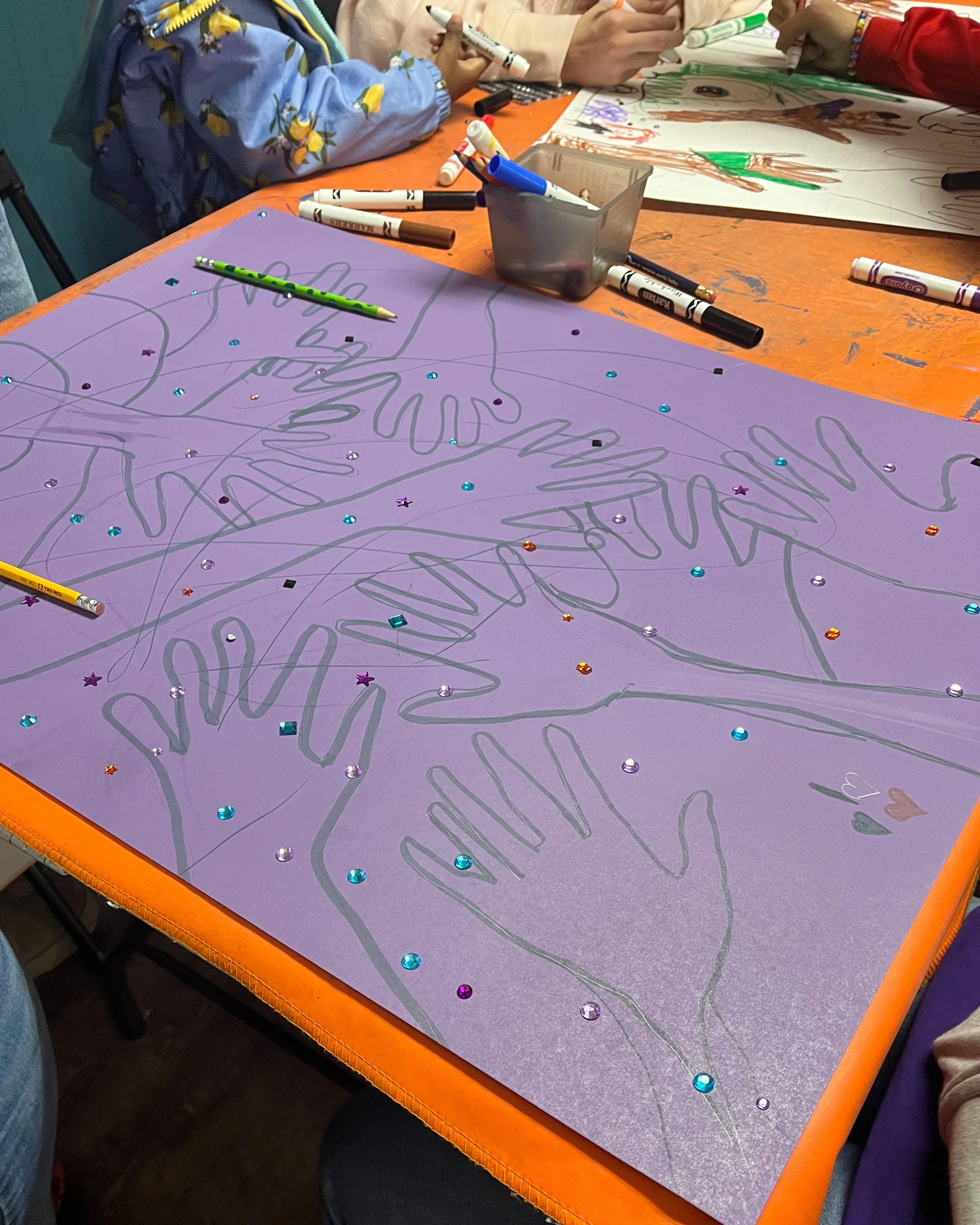Hand-decorated purple poster board with rhinestones and marker drawings created during a children’s craft activity.