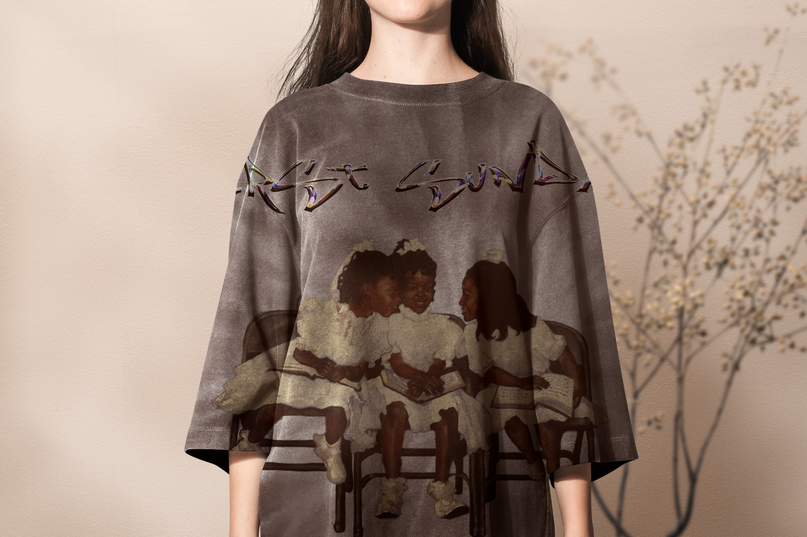 A person wearing a gray oversized sweatshirt featuring a graphic of three women sitting on chairs, smiling and holding books, with colorful, abstract text above them.