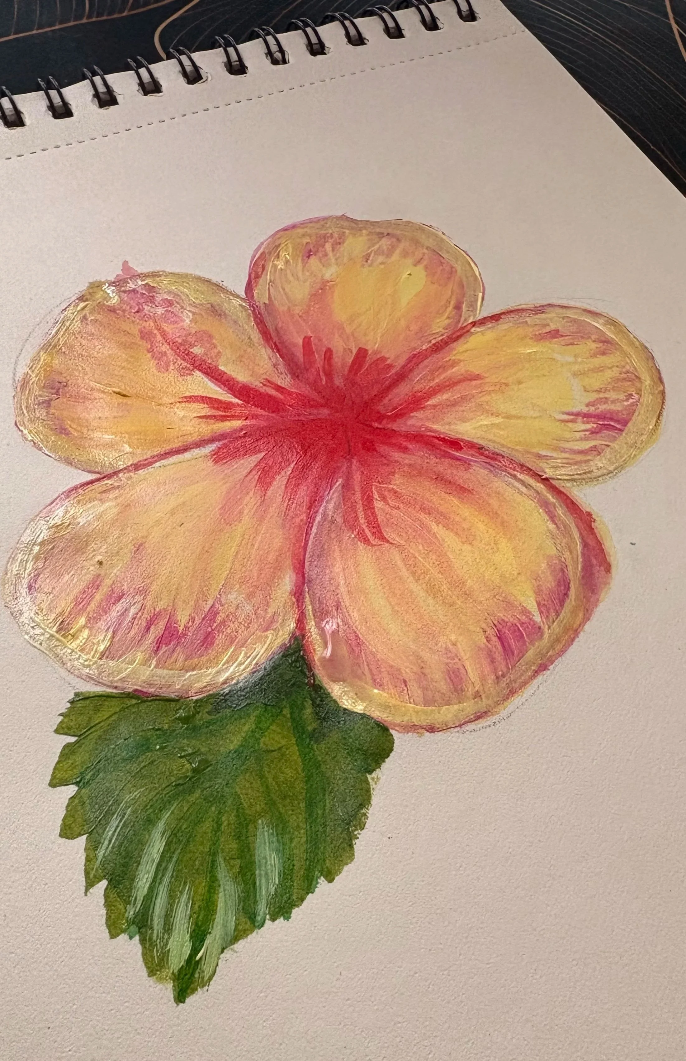 A painted picture of a yellow and pink flower with a green leaf below it, on a white piece of paper.