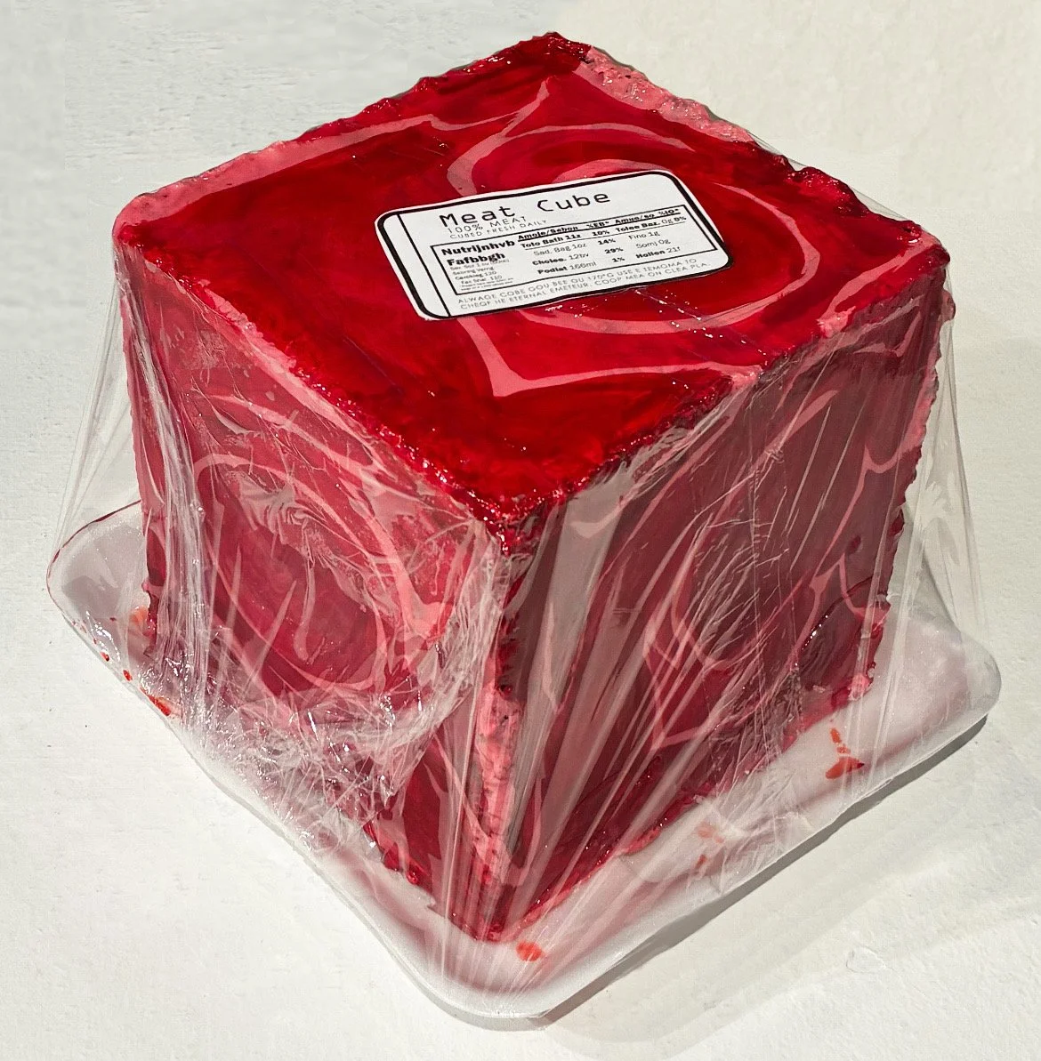 2025, Meat Cube. Steel, acetylene welding, acrylic paint, tabletop epoxy, plastic wrap, Styrofoam trays, Adobe Photoshop for label, fake blood mixture (soy sauce, water, food coloring, corn syrup.)