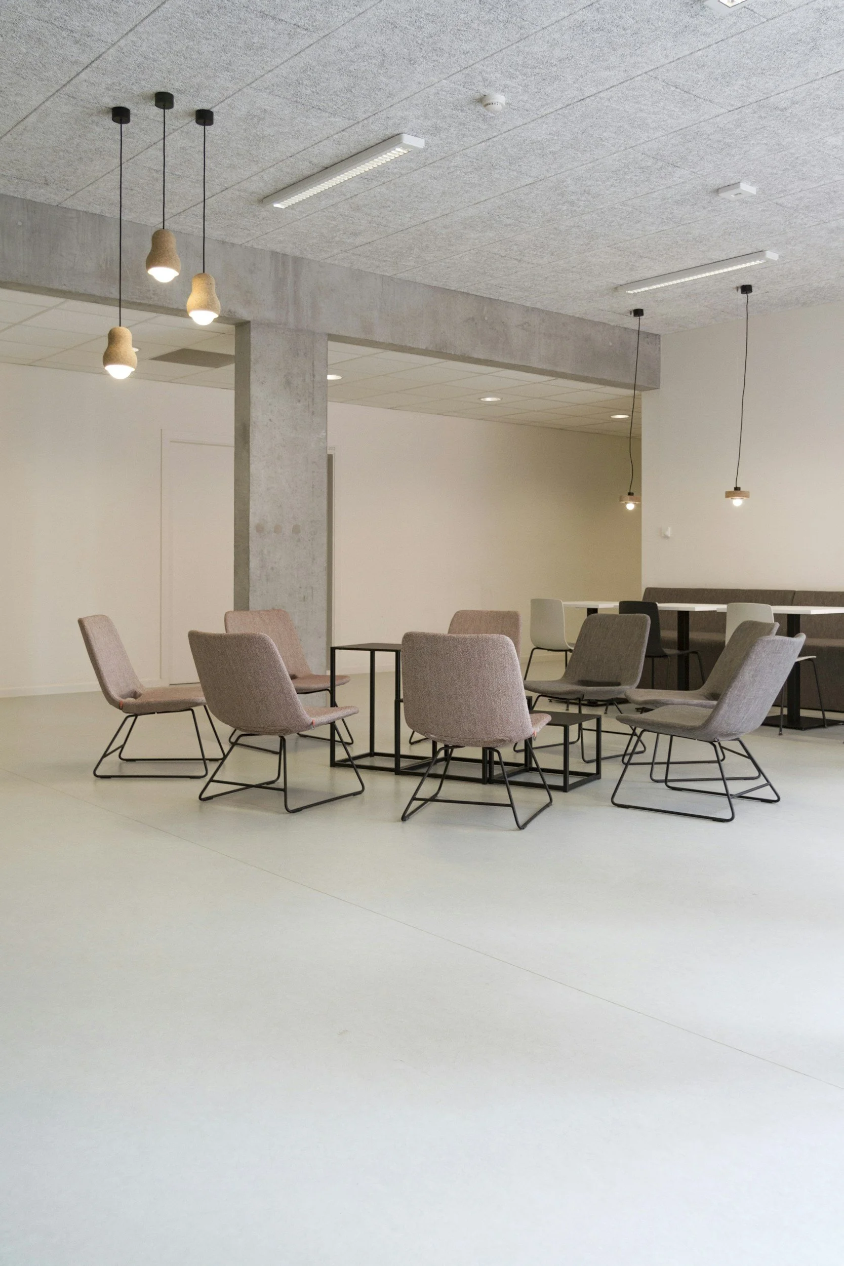 Modern minimalist room with beige chairs and pendant lighting.