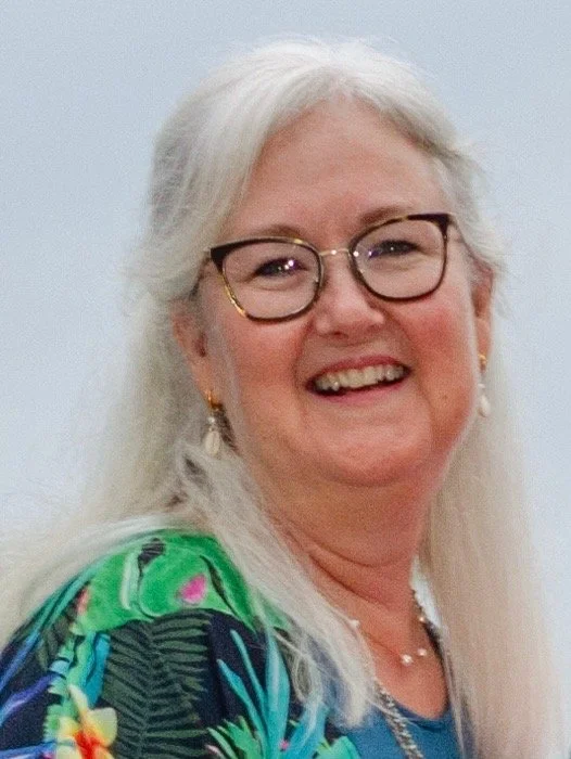 A Woman in glasses, smiling as she recounts her experience working with SOund Legacy on her father's documentary project.