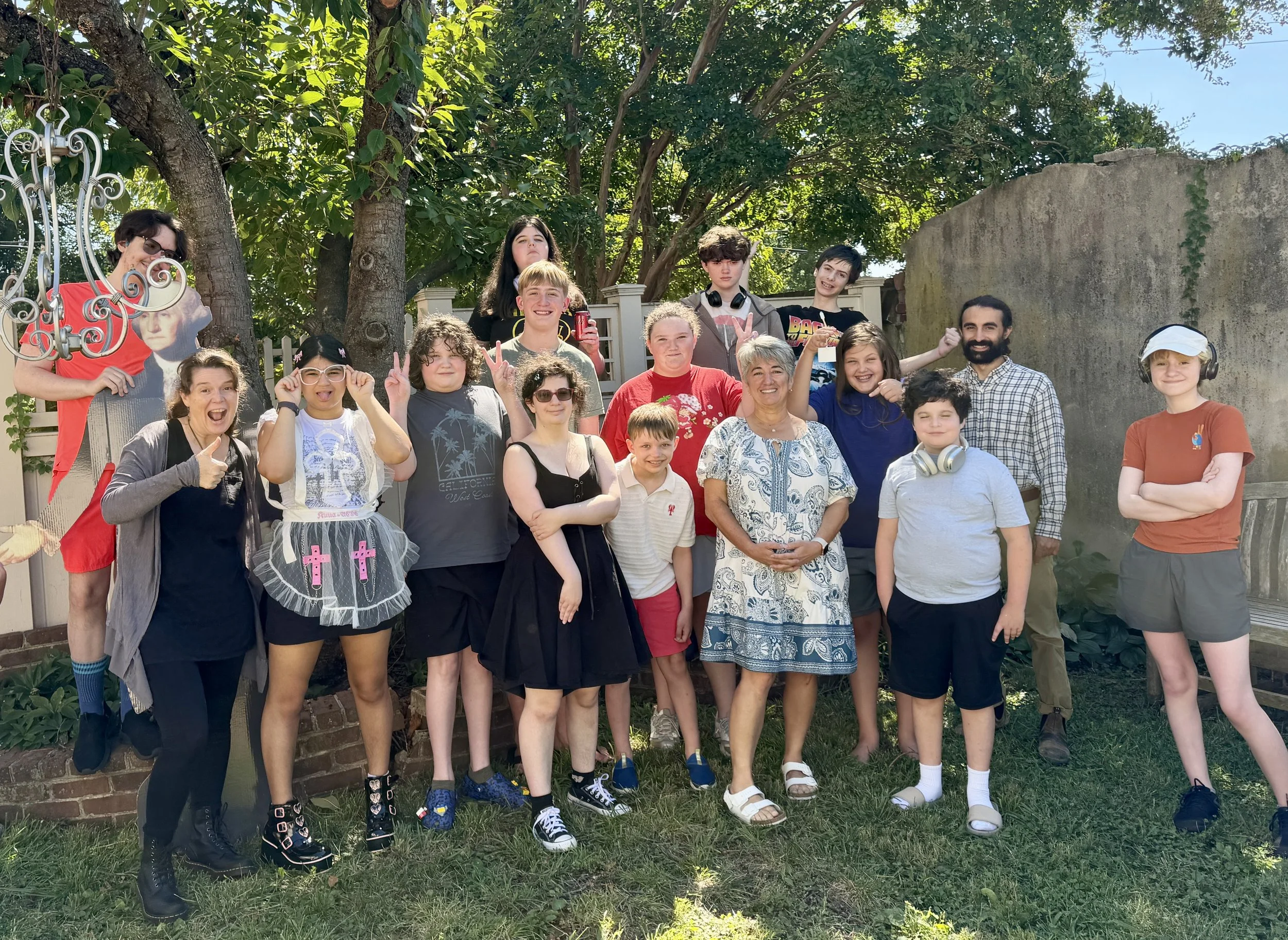 Embark Center students and staff smiling together under a tree on the first day of the 2026–27 year, joined by a cardboard George Washington.