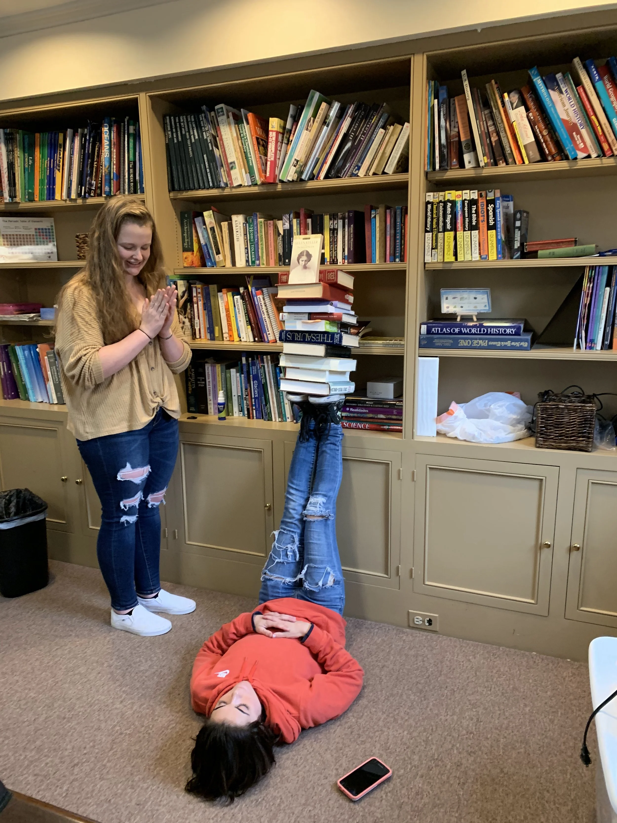 Students experimenting with balancing a stack of books in a learning space, illustrating curiosity and self-directed learning