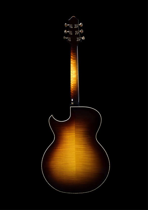 Back view of a guitar in a tobacco-burst coloring and extra fine curly maple with a Florentine cutaway