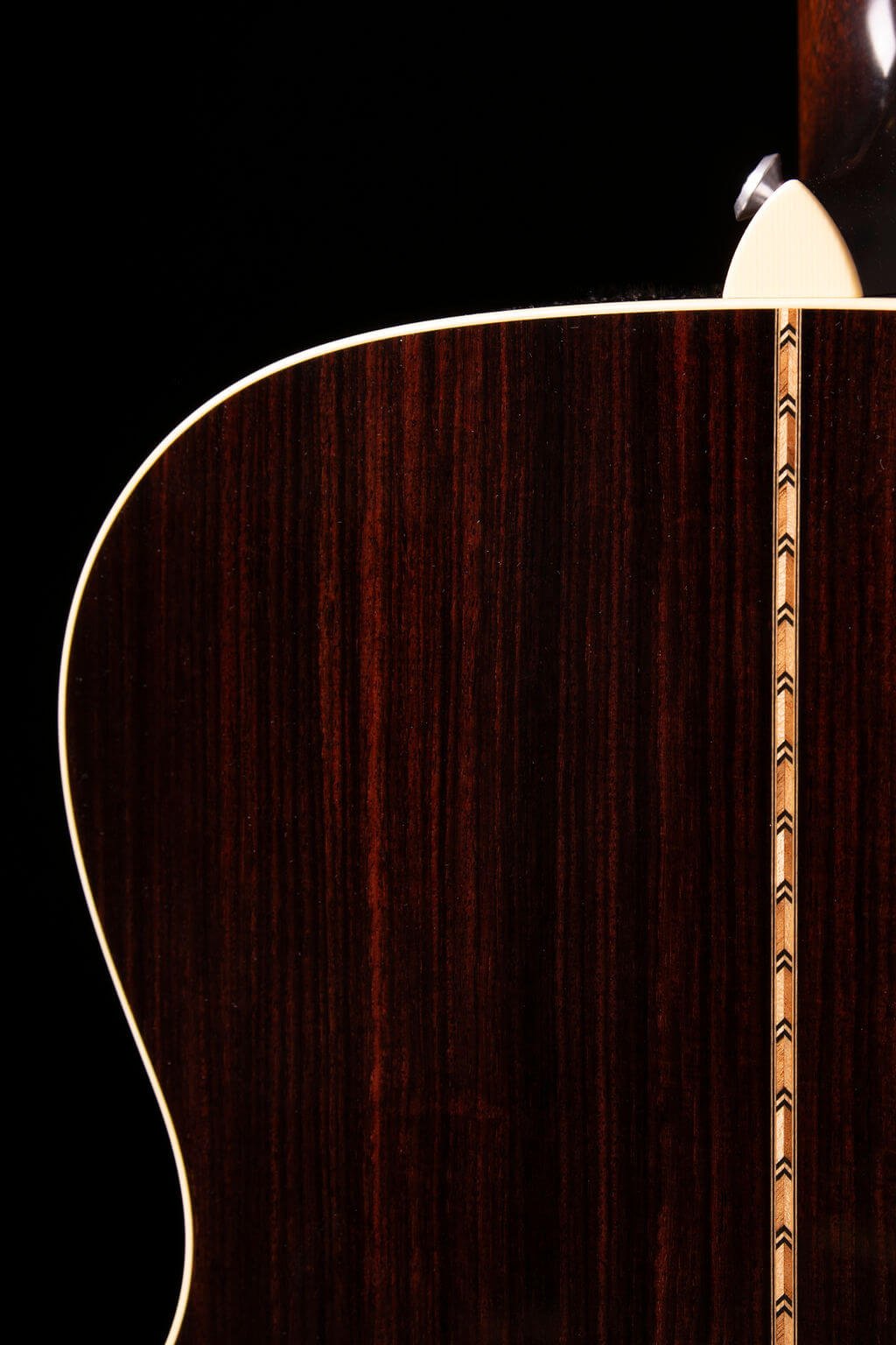 Closeup view of the back of a guitar with decorative inlay
