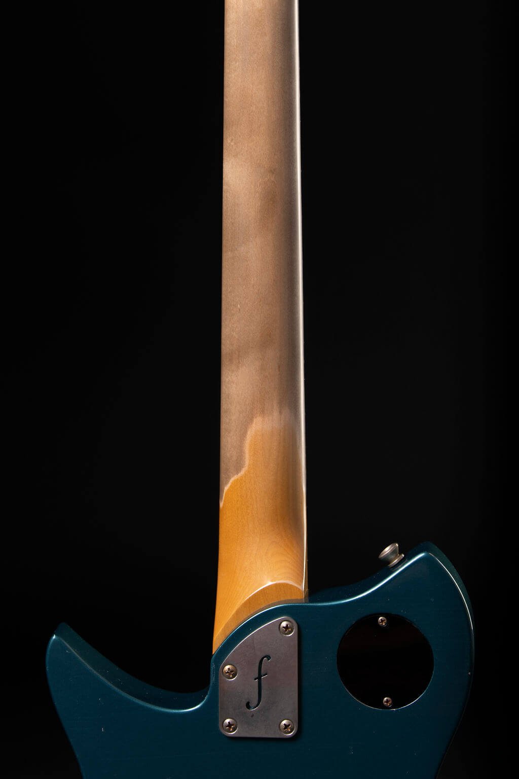 Closeup view of the back of an electric guitar’s neck showing wear