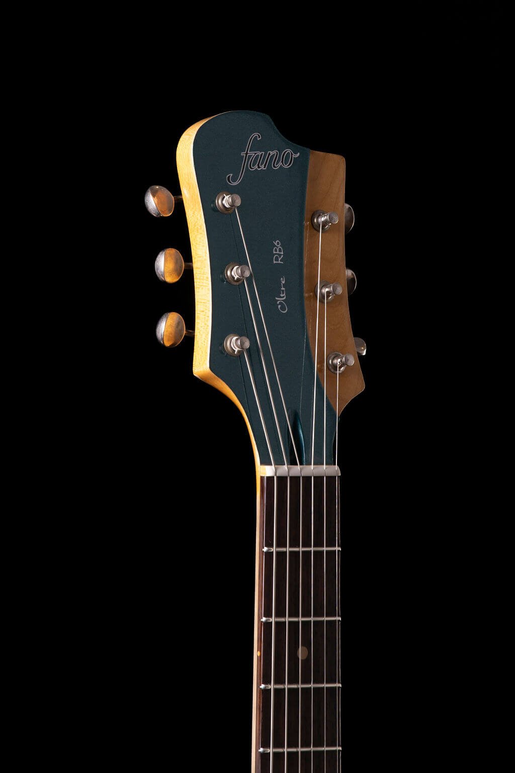 Closeup view of an electric guitar’s German Carve headstock with Fano logo and “Oltre RB6”