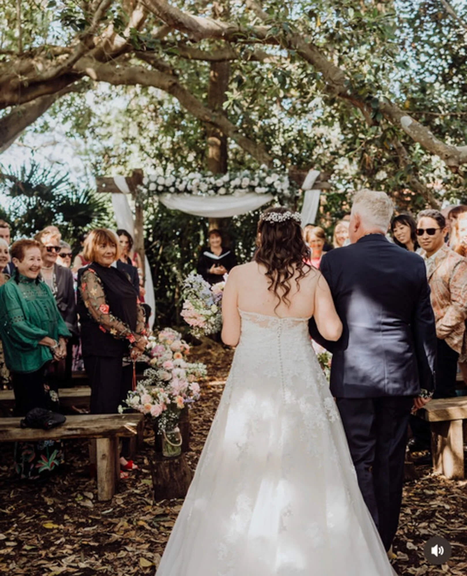 Bride and groom walking down the aisle during an outdoor wedding ceremony with guests watching and smiling.