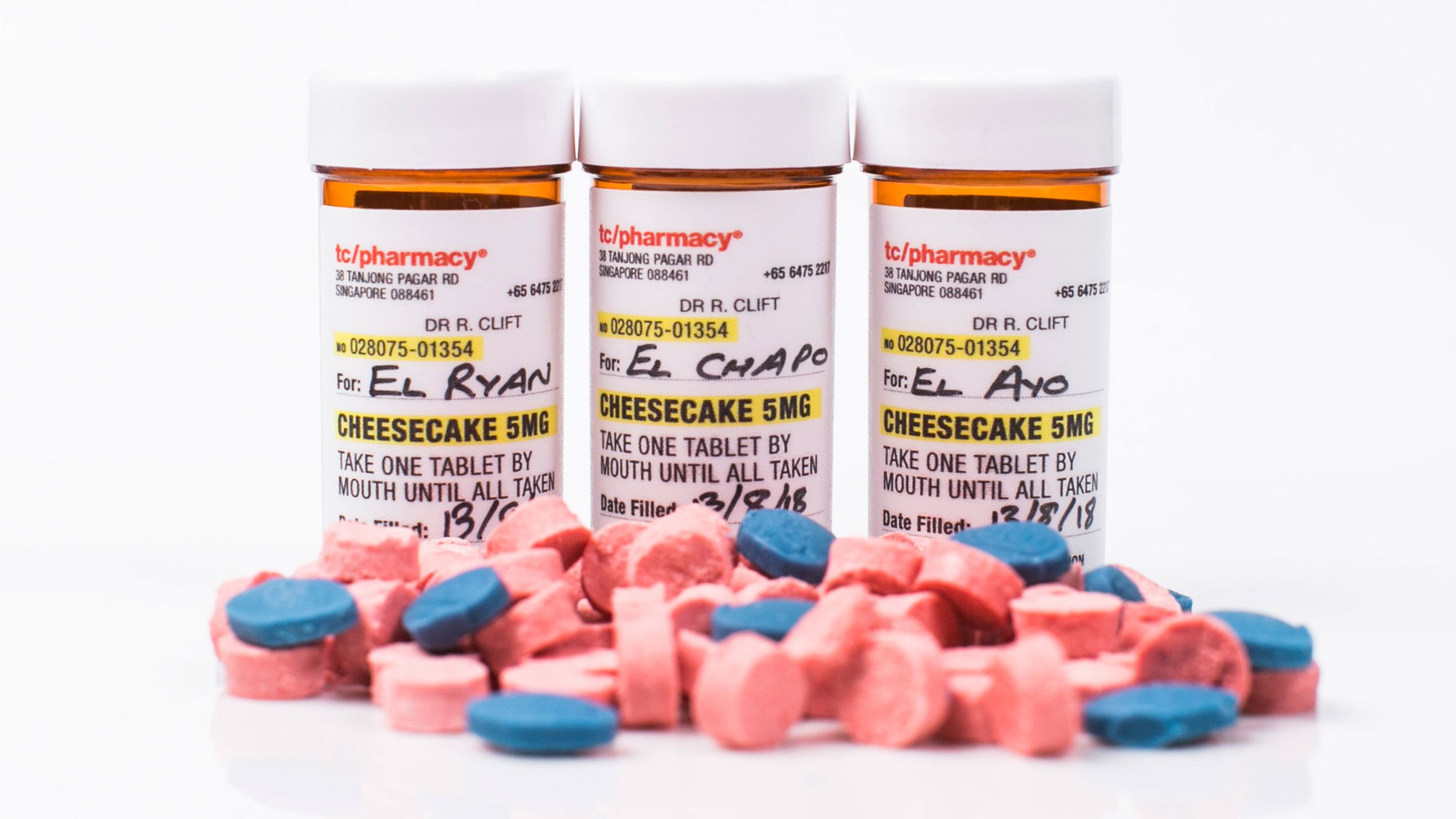 Packaging design for a palette cleanser in small pharmacy bottles. On the label are details including “Cheesecake 5mg” and “Take one table by mouth until all taken”. A small pile of pink and blue “pills” sits in front of the three bottles.