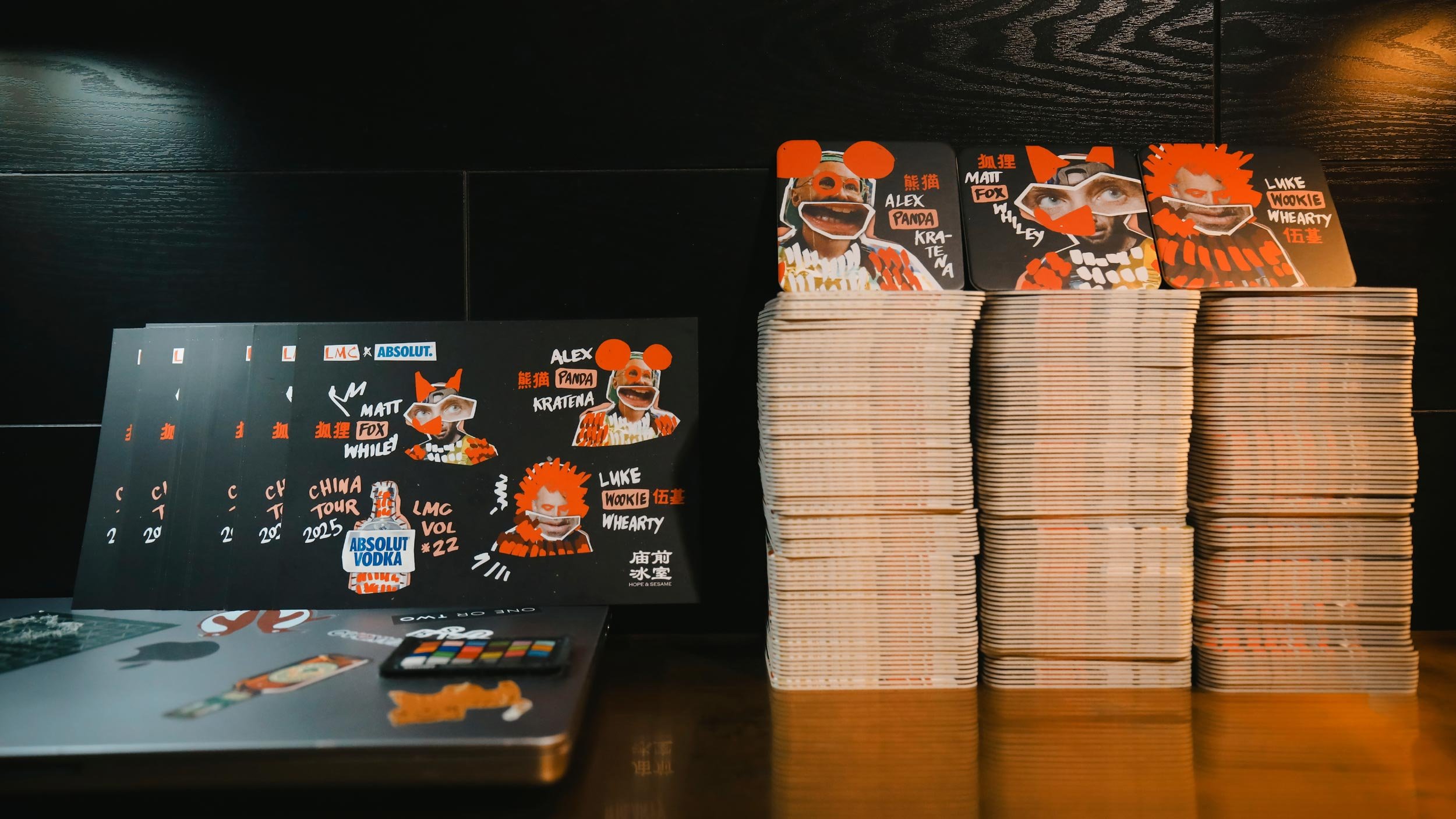 LMC Vol#22 Menus leaning against the back of a bar. Three piles of coasters sit to the right, one for Alex Panda Kratena, one for Matt Fox Whiley and one for Luke Wookie Whearty.