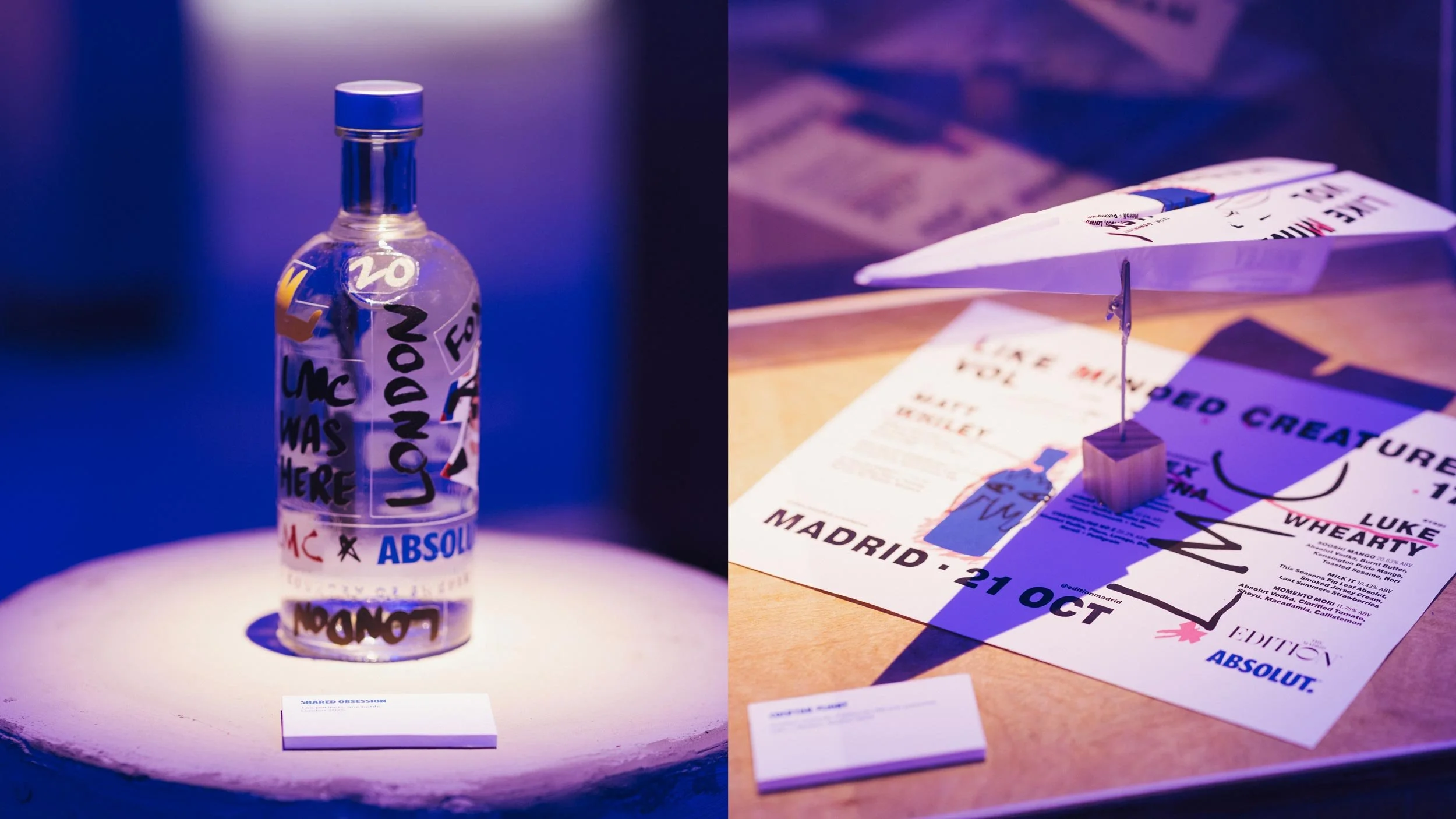 Bottle of Absolut Vodka covered in LMC stickers such as “LMC WAS HERE” and “LONDON” (left) and a menu from Like Minded Creatures Vol 17 in Madrid sits on a wooden plinth with one menu folded into a paper aeroplane on top of it (right).