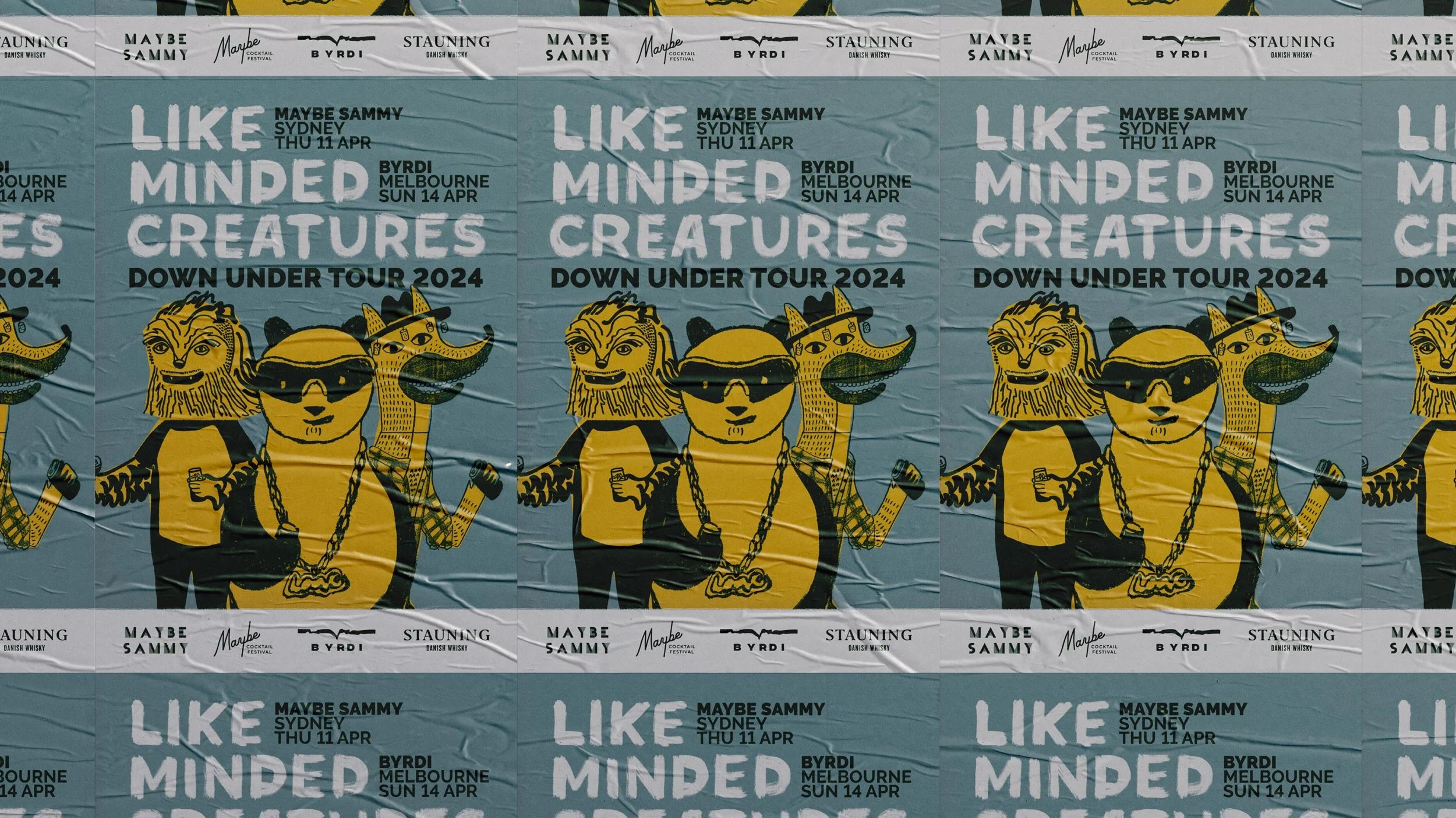 Rock posters pasted up on a brick wall promoting Like Minded Creatures Down Under Tour 2024 in Sydney and Melbourne. A blurred person passes in the foreground.