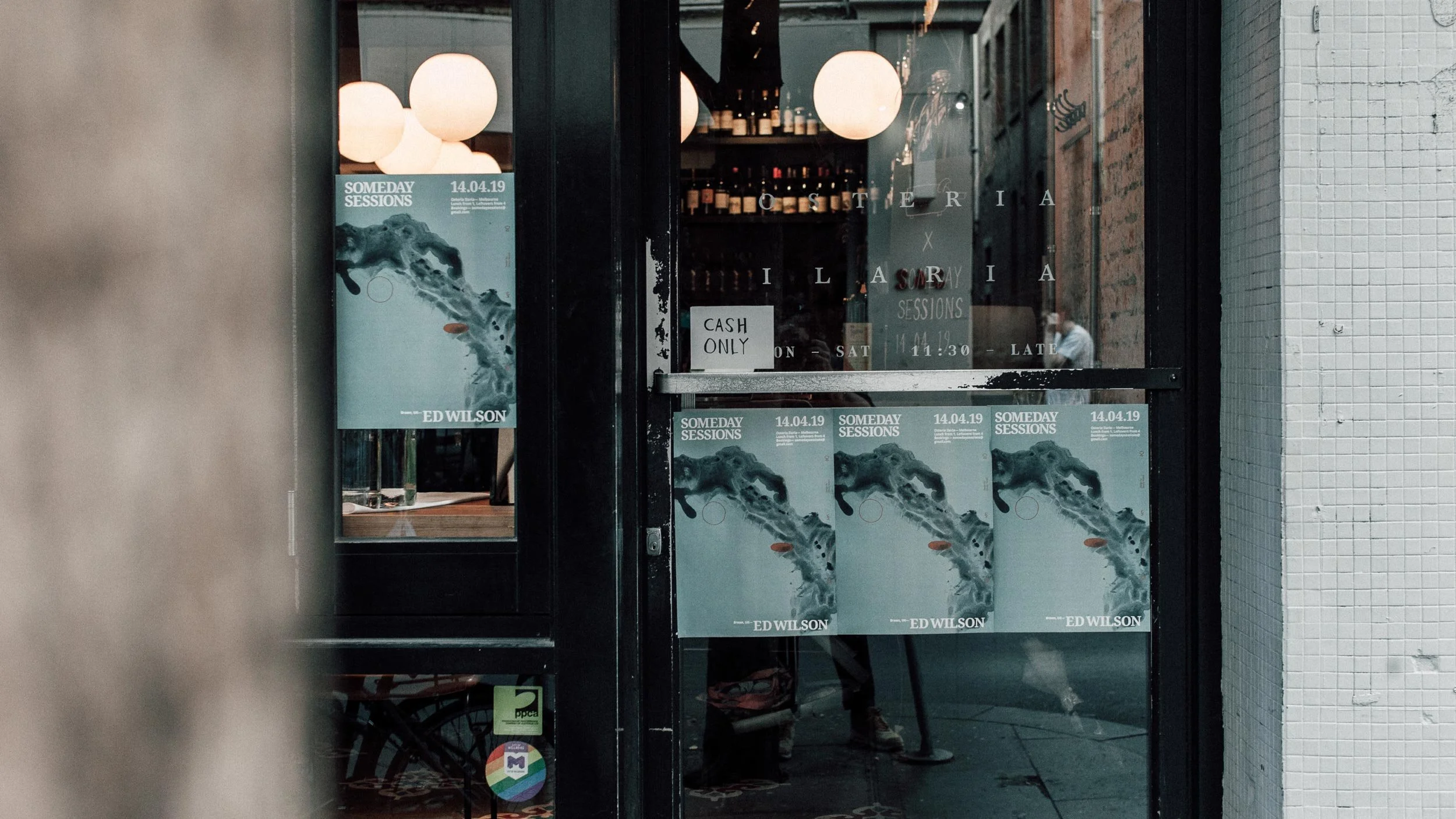 Three Someday Sessions posters side by side in the Osteria Ilaria door and window.