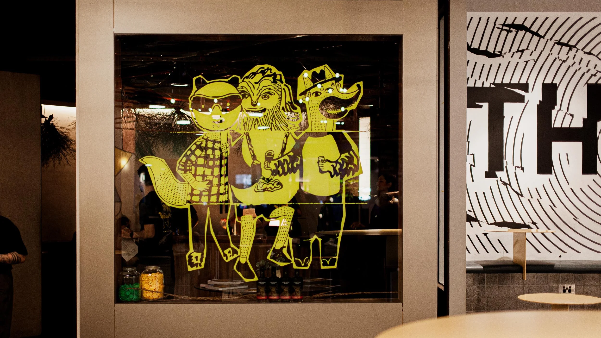 Front entrance of Byrdi bar in Melbourne. There is a bright yellow illustrated decal on the window of a panda, wookie and fox creature.
