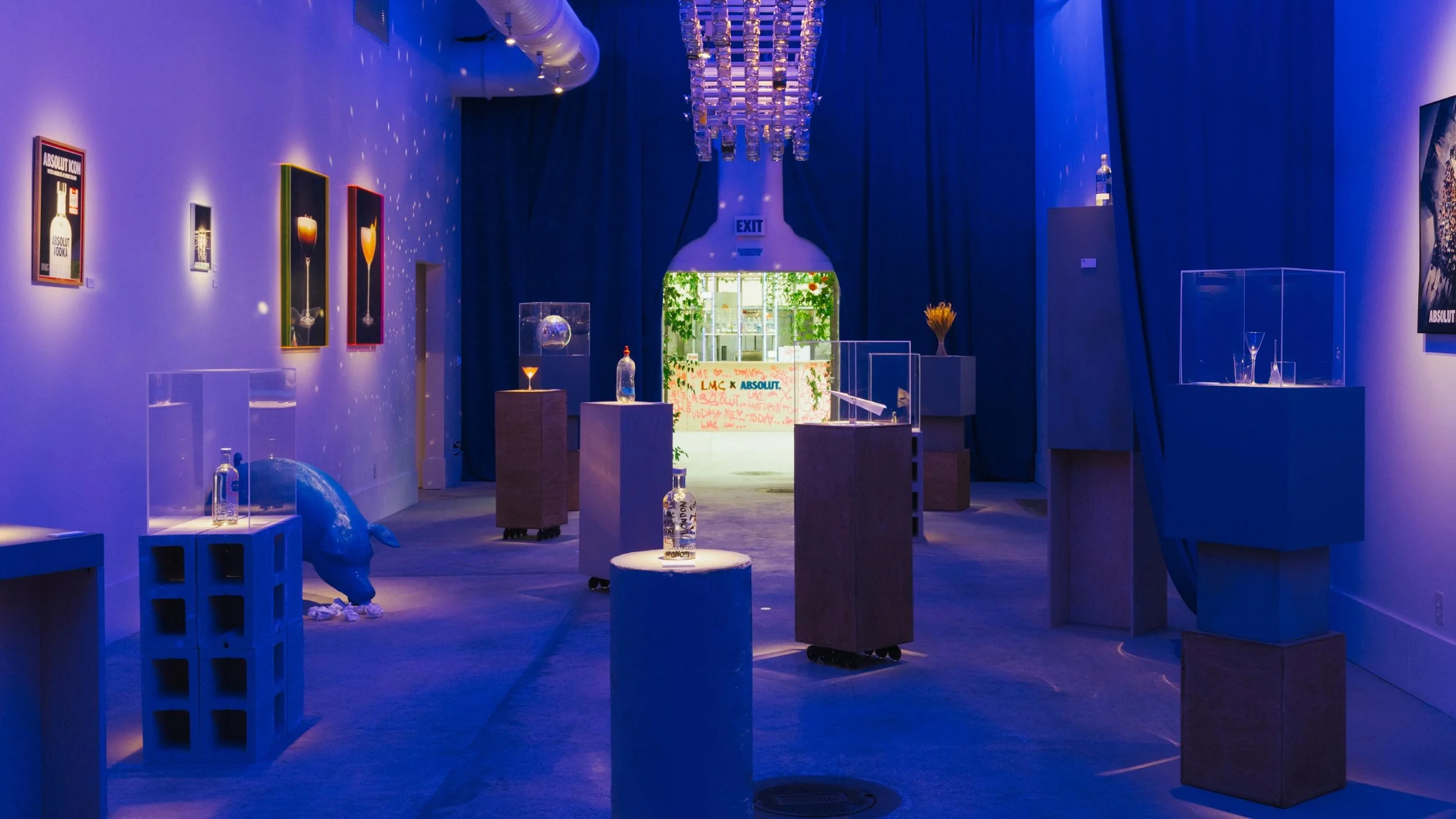 Inside the Absolut Studio at Tales of the Cocktail New Orleans looking through to a wooden bar with LMC x Absolut logo lockup on the front. Pink spray painted words cover the bar.